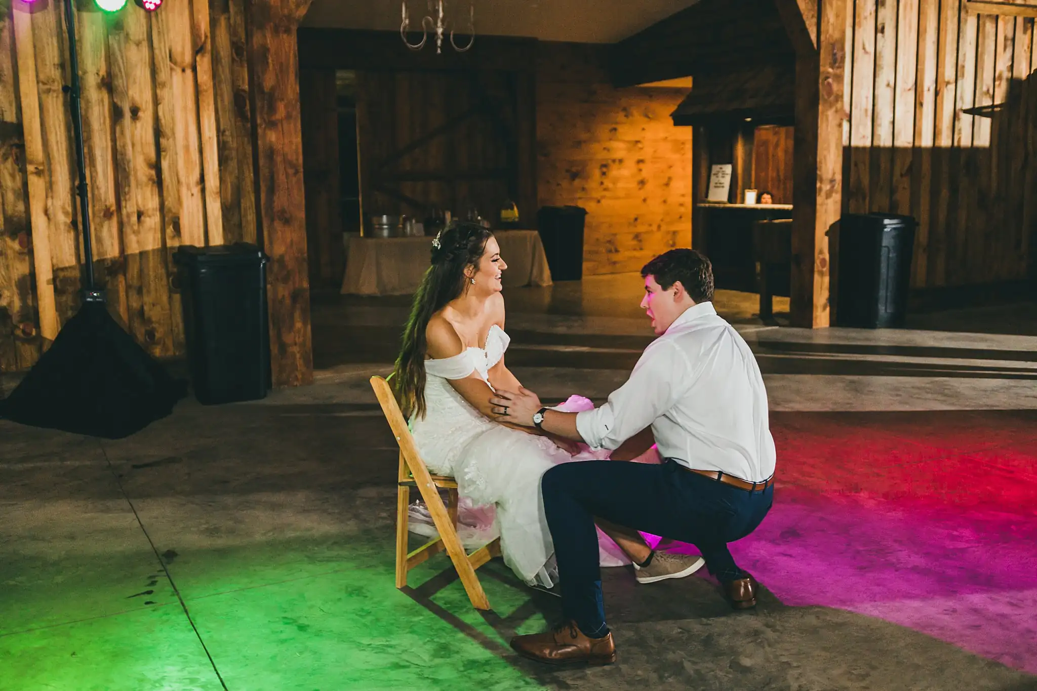 Barn at Harper Pines Wedding Thomaston, GA Atlanta Wedding Photographers Garter Toss: the groom kneeling for the garter, at their wedding at the Barn at Harper Pines in Thomaston, GA
