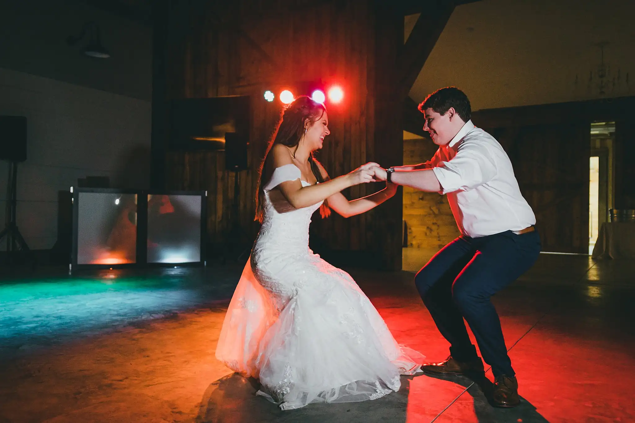 Barn at Harper Pines Wedding Thomaston, GA Atlanta Wedding Photographers Wedding Reception: the couple dancing under colored lights, at their wedding at the Barn at Harper Pines in Thomaston, GA