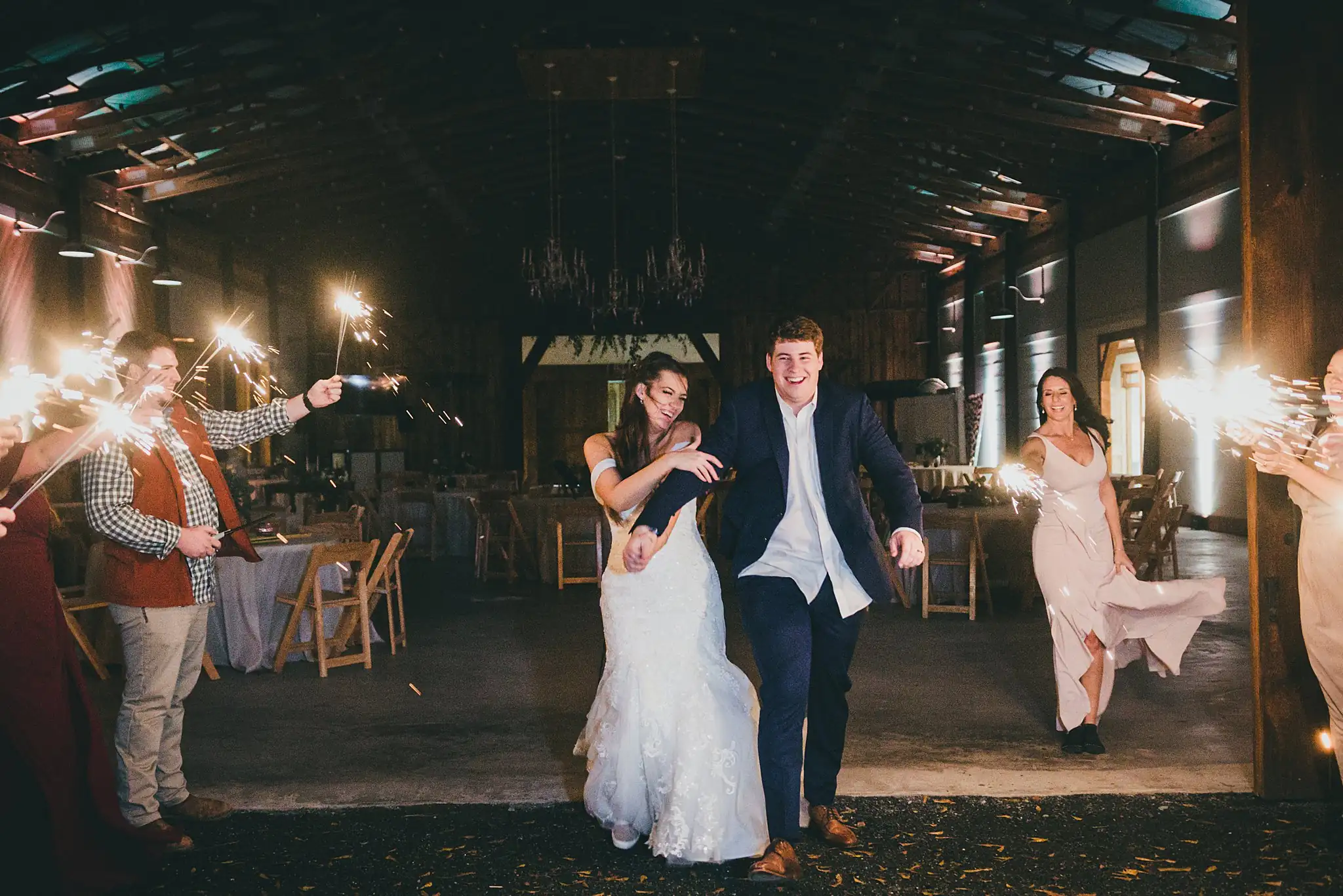 Barn at Harper Pines Wedding Thomaston, GA Atlanta Wedding Photographers Sparkler Exit: the couple walking through their guests' sparklers, at their wedding at the Barn at Harper Pines in Thomaston, GA