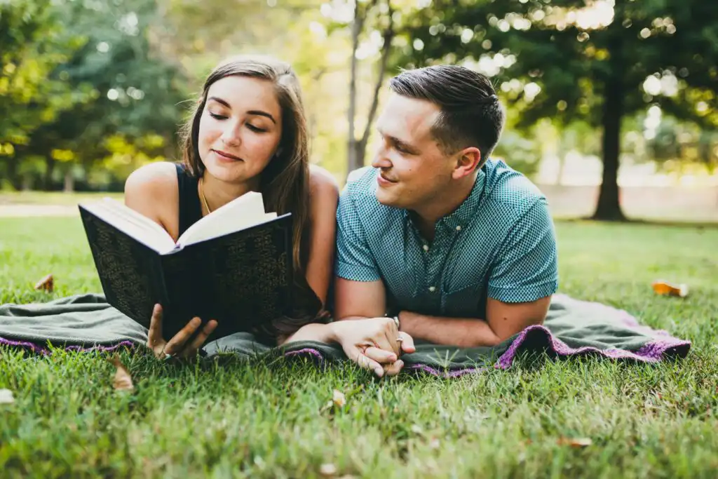 Engagement Portraits: a couple lying on a blanket reading together, during their engagement session in Piedmont Park in Atlanta, GA