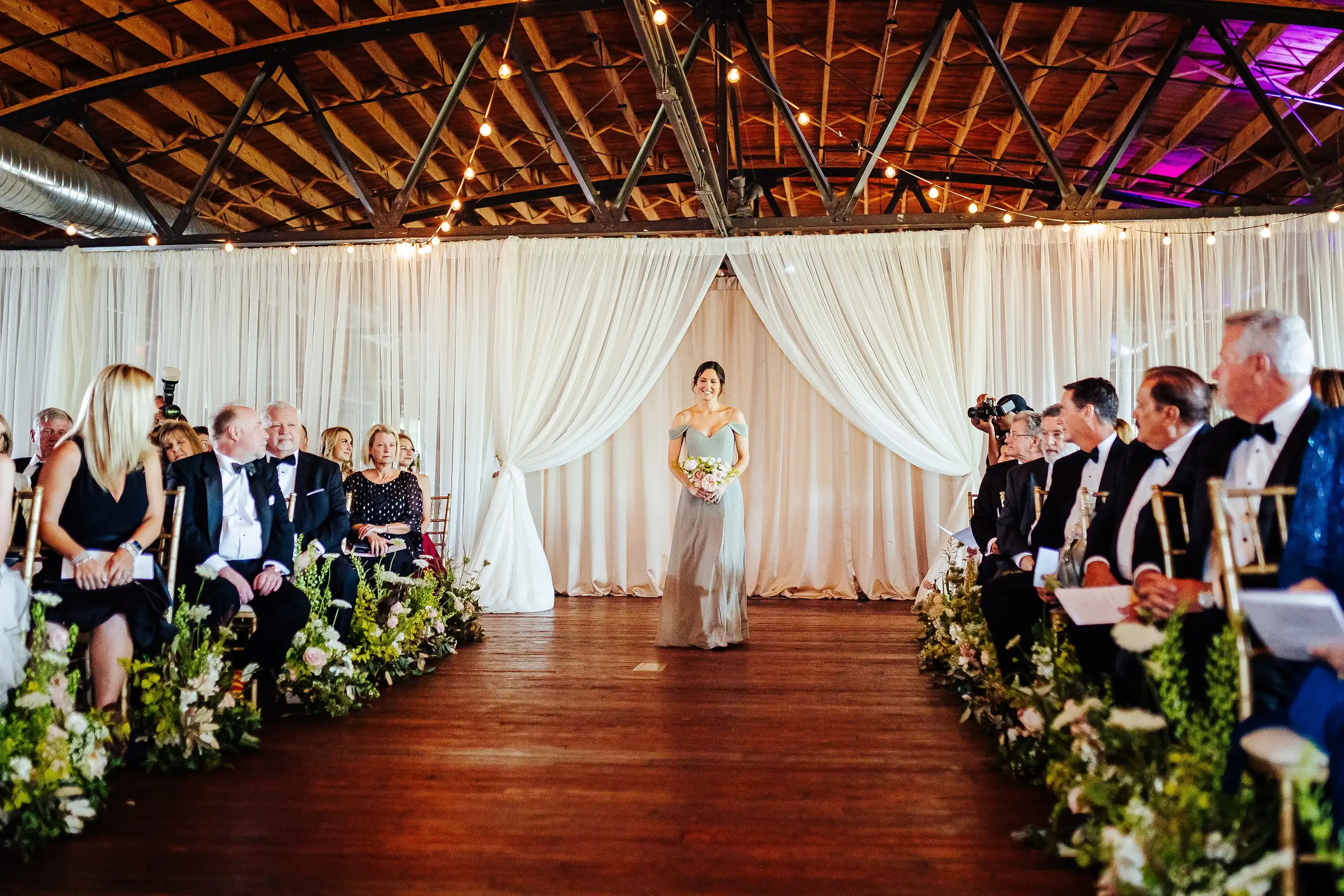Processional: a bridesmaid walking the aisle in sage, at their wedding at Summerour Studio in Atlanta, GA
