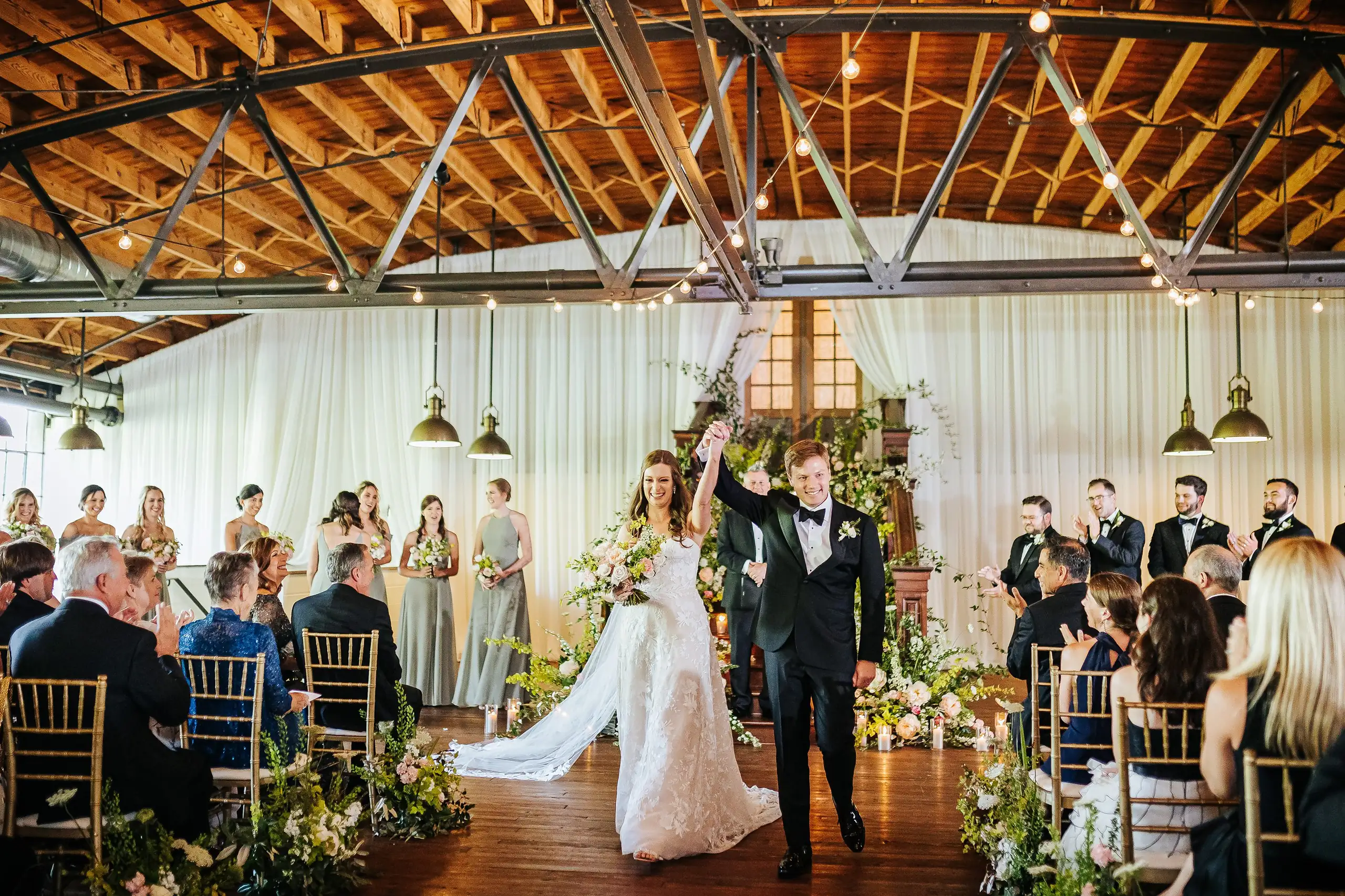 Recessional: the groom's fist raised as the couple head back up the aisle, at their wedding at Summerour Studio in Atlanta, GA