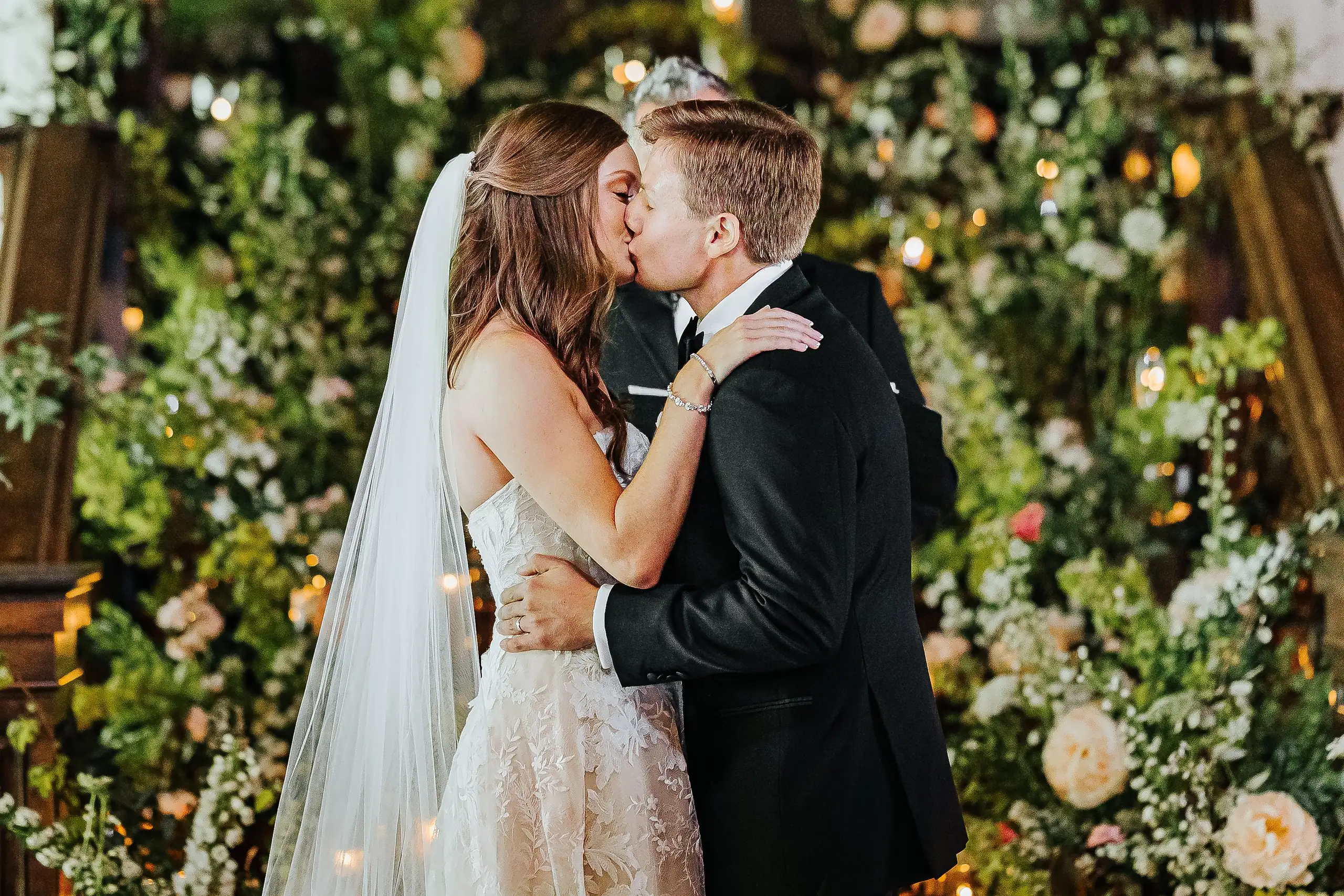 Wedding Ceremony: the first kiss in front of the floral arch, at their wedding at Summerour Studio in Atlanta, GA
