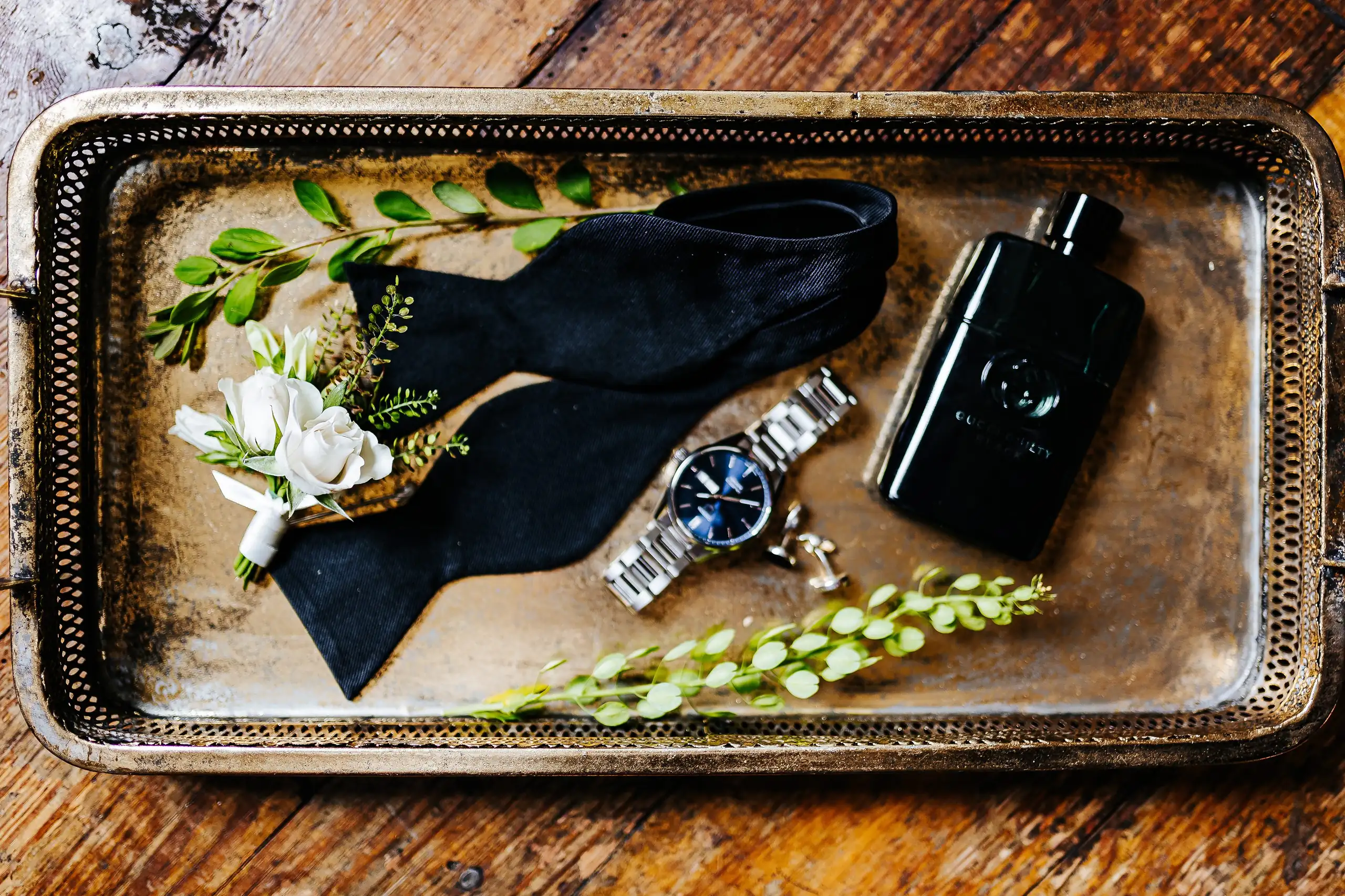 Wedding Details: the groom's bow tie, watch, cologne and boutonniere on a silver tray, at a wedding at Summerour Studio in Atlanta, GA