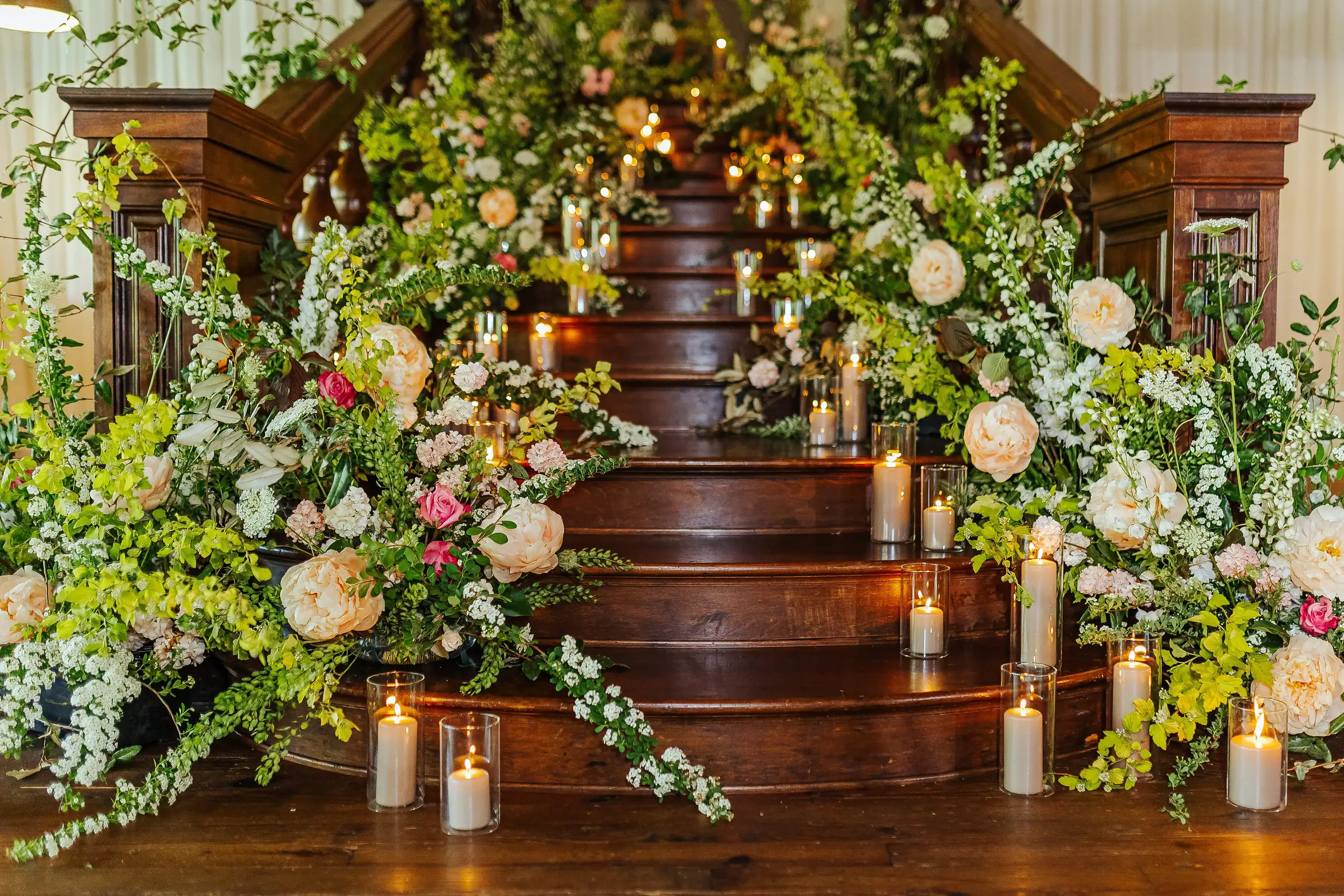Reception Details: the staircase banked with spring flowers and candles, at a wedding at Summerour Studio in Atlanta, GA
