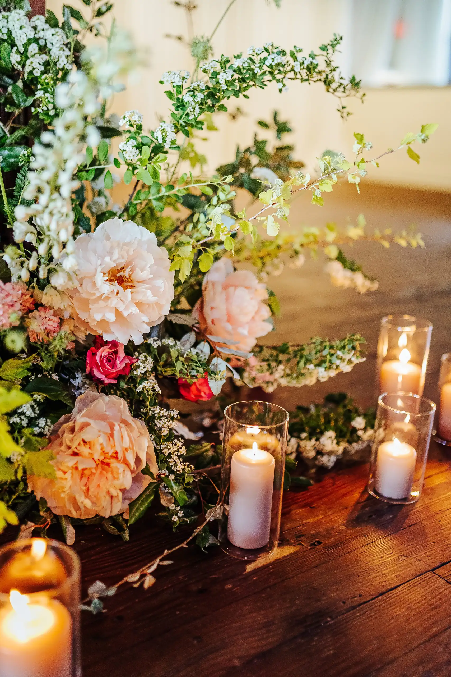 Reception Details: garden roses and candlelight on a wooden table, at a wedding at Summerour Studio in Atlanta, GA