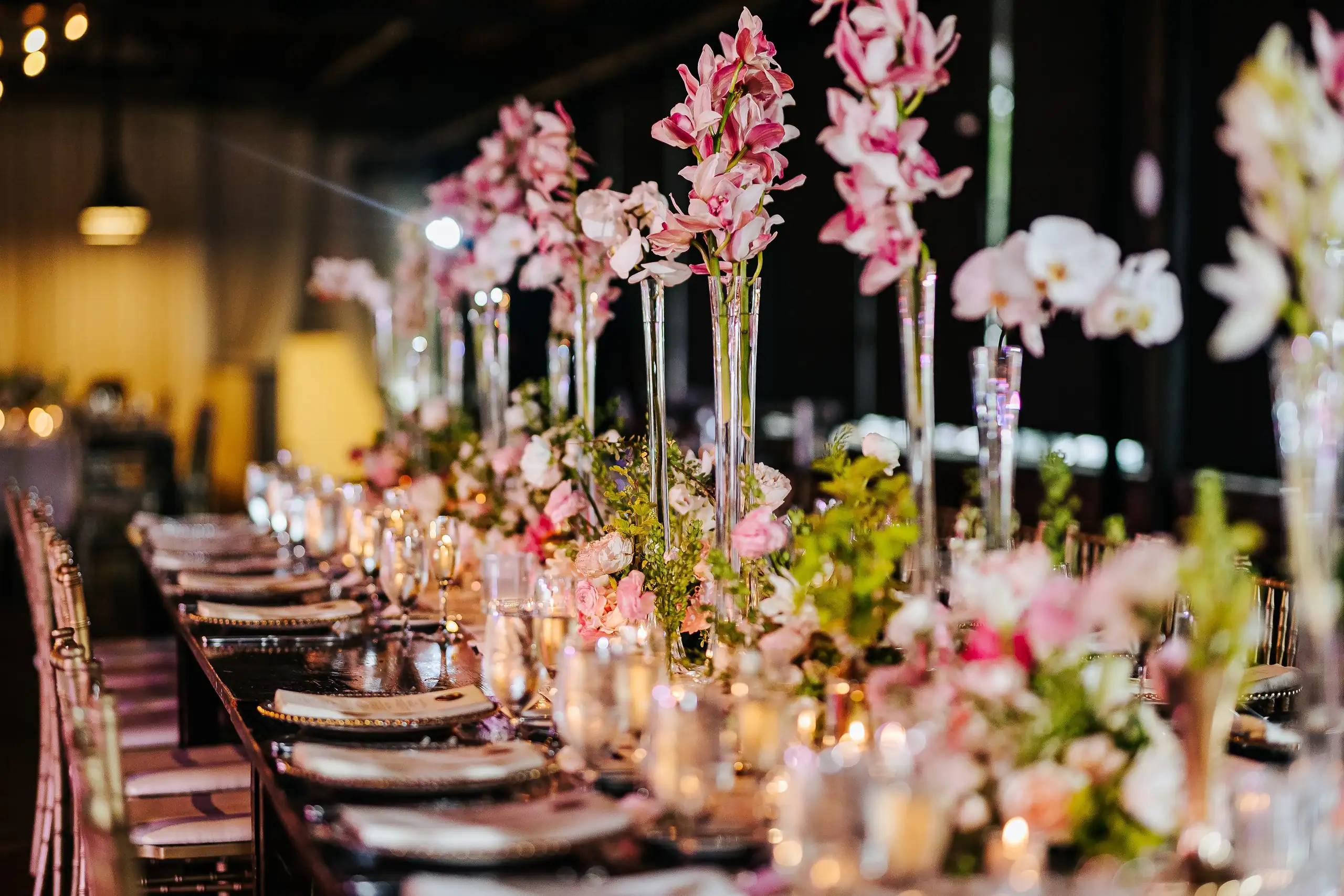 Reception Details: the long table beneath tall pink orchids, at a wedding at Summerour Studio in Atlanta, GA