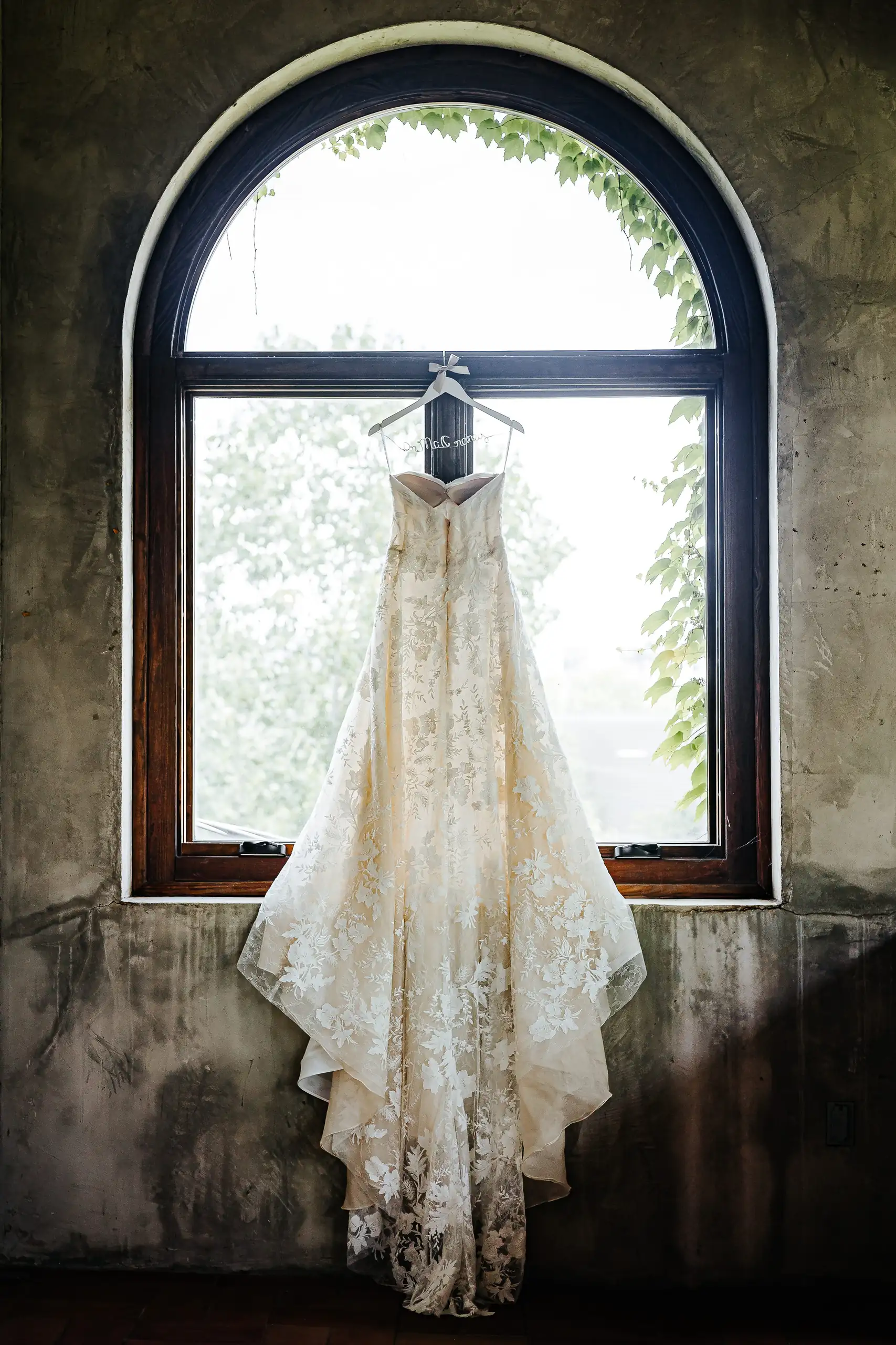 Wedding Details: the gown hanging in the arched window, at a wedding at Summerour Studio in Atlanta, GA