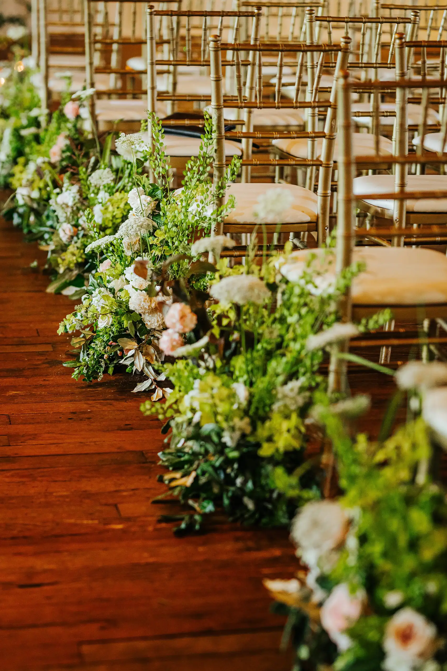 Wedding Ceremony: the aisle lined with spring flowers and gold chairs, at their wedding at Summerour Studio in Atlanta, GA