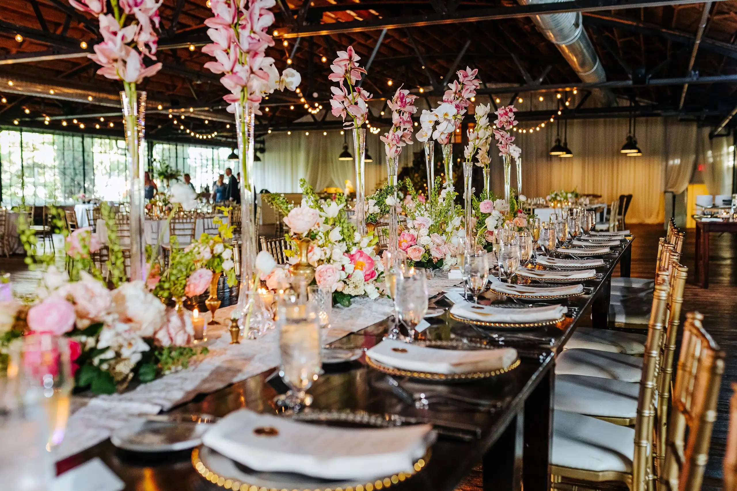 Reception Details: the long table under tall orchids and string lights, at a wedding at Summerour Studio in Atlanta, GA
