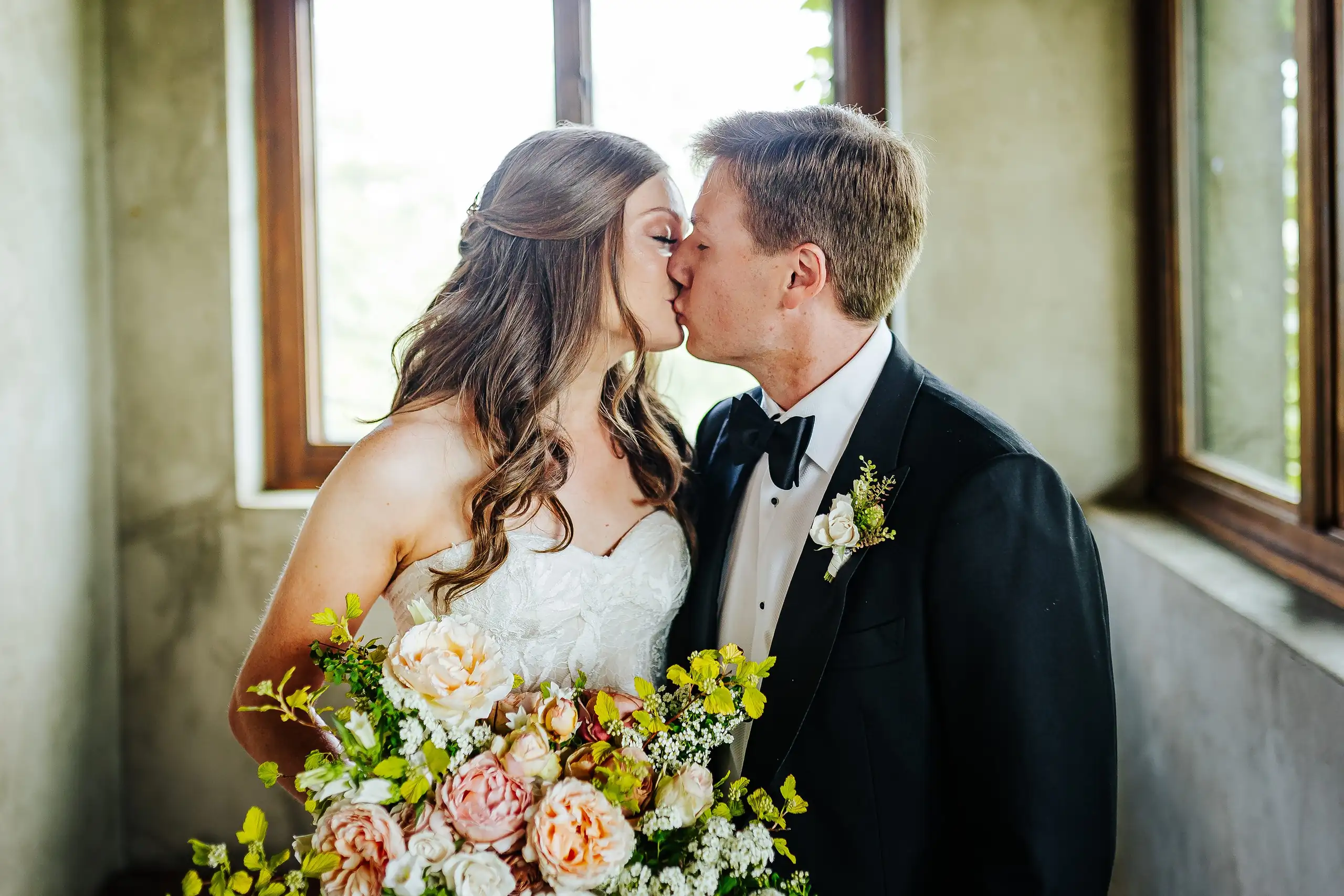 Wedding Formals: the couple kissing in the window light, at their wedding at Summerour Studio in Atlanta, GA