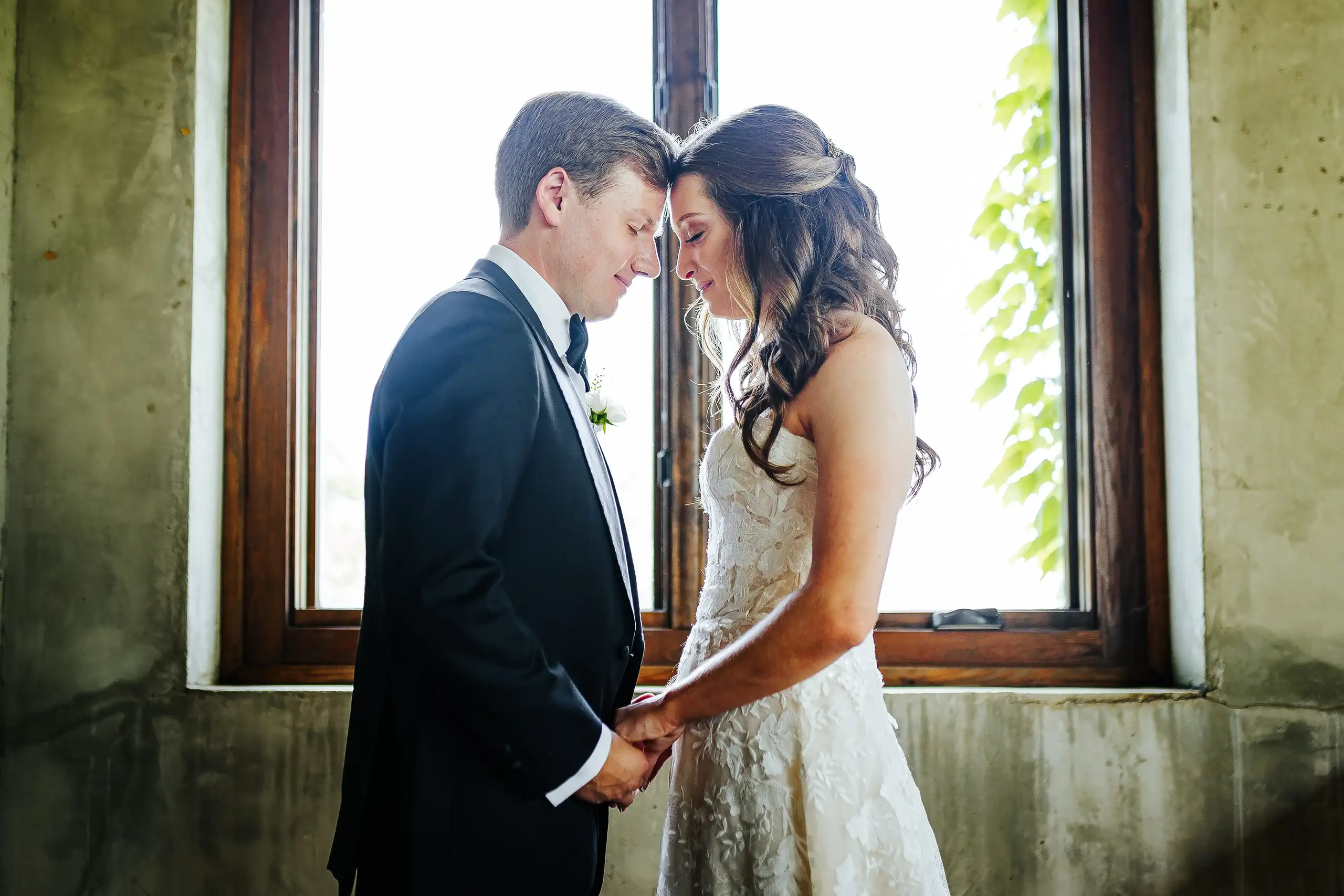 Wedding Formals: the couple forehead to forehead by the window, at their wedding at Summerour Studio in Atlanta, GA
