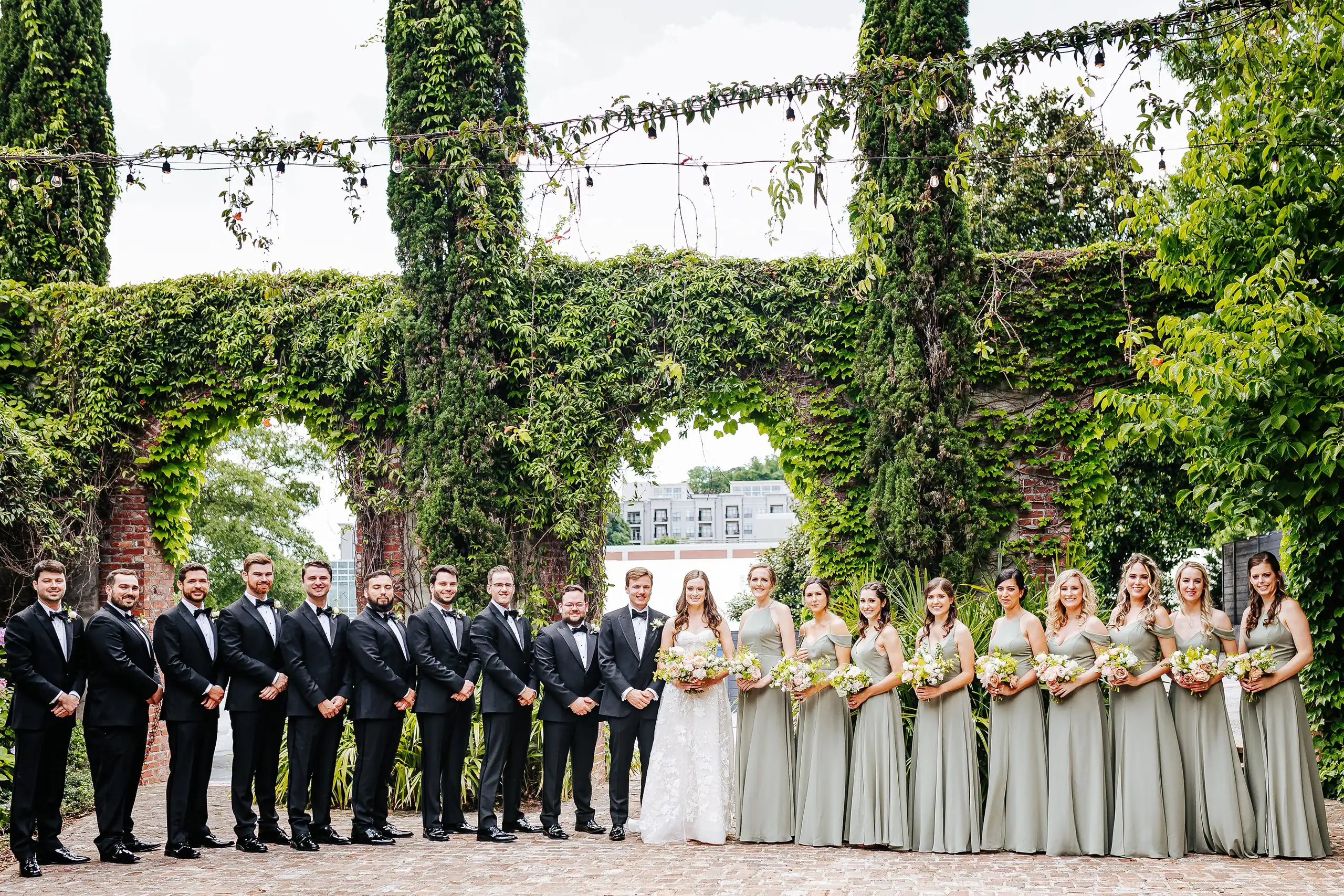 Wedding Party: the whole wedding party beneath the ivy arches, at their wedding at Summerour Studio in Atlanta, GA