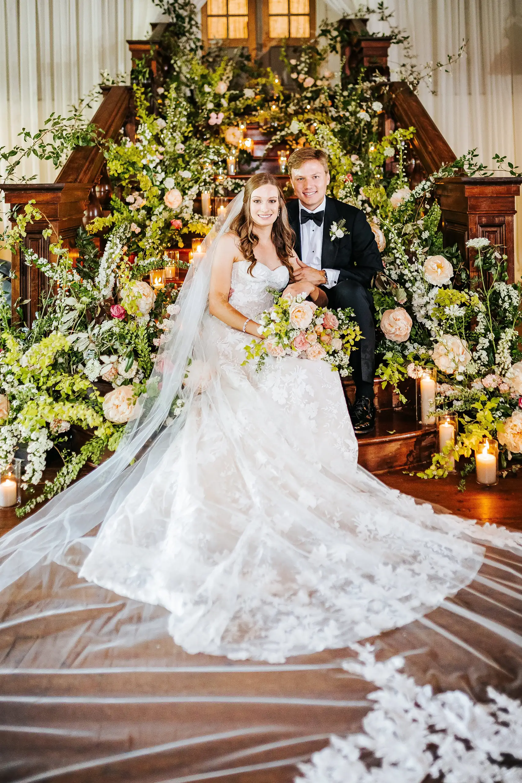 Bridal Portraits: the bride on the flower-covered staircase with her train spread, at their wedding at Summerour Studio in Atlanta, GA