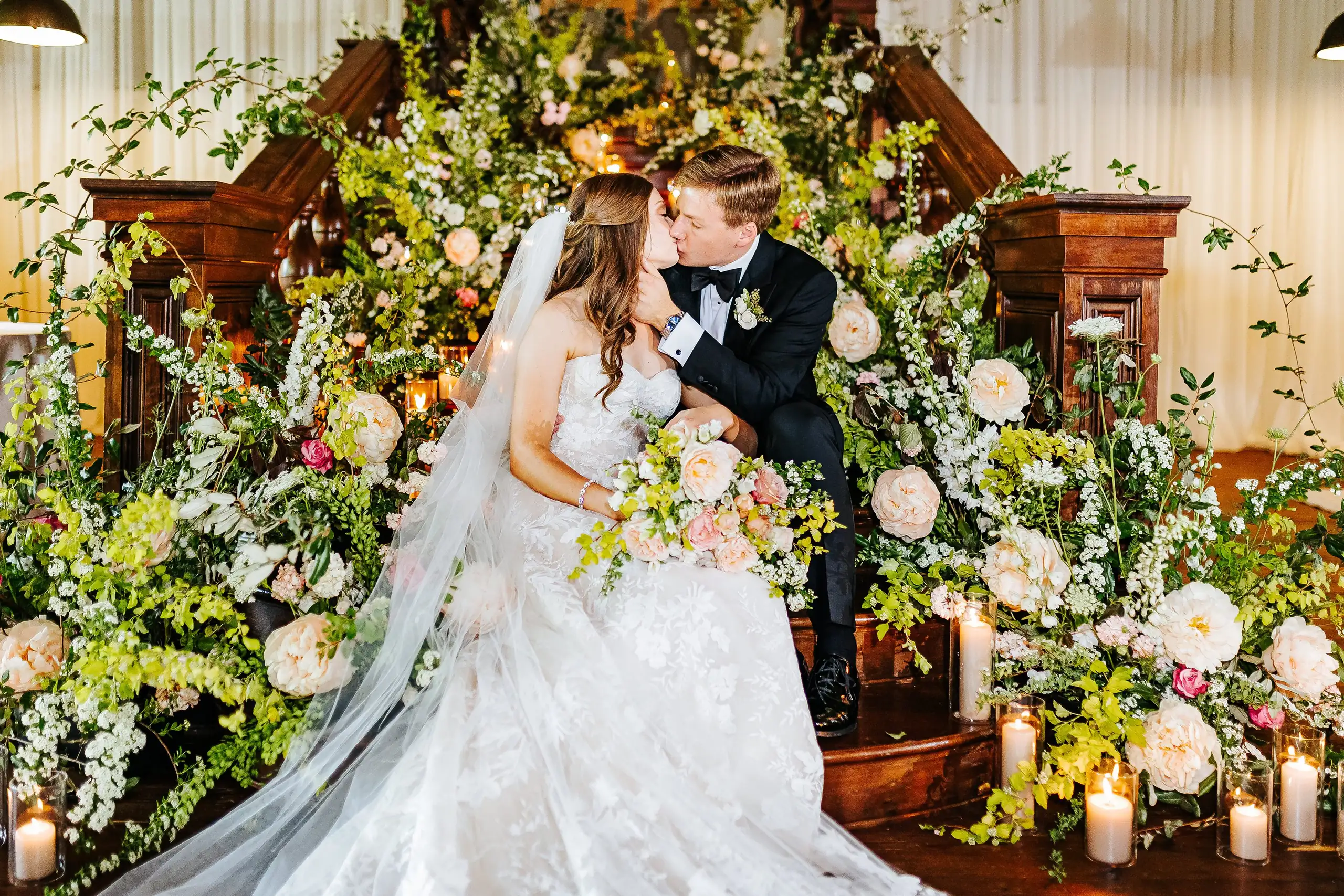 Wedding Formals: the couple kissing on the flower-covered staircase, at their wedding at Summerour Studio in Atlanta, GA