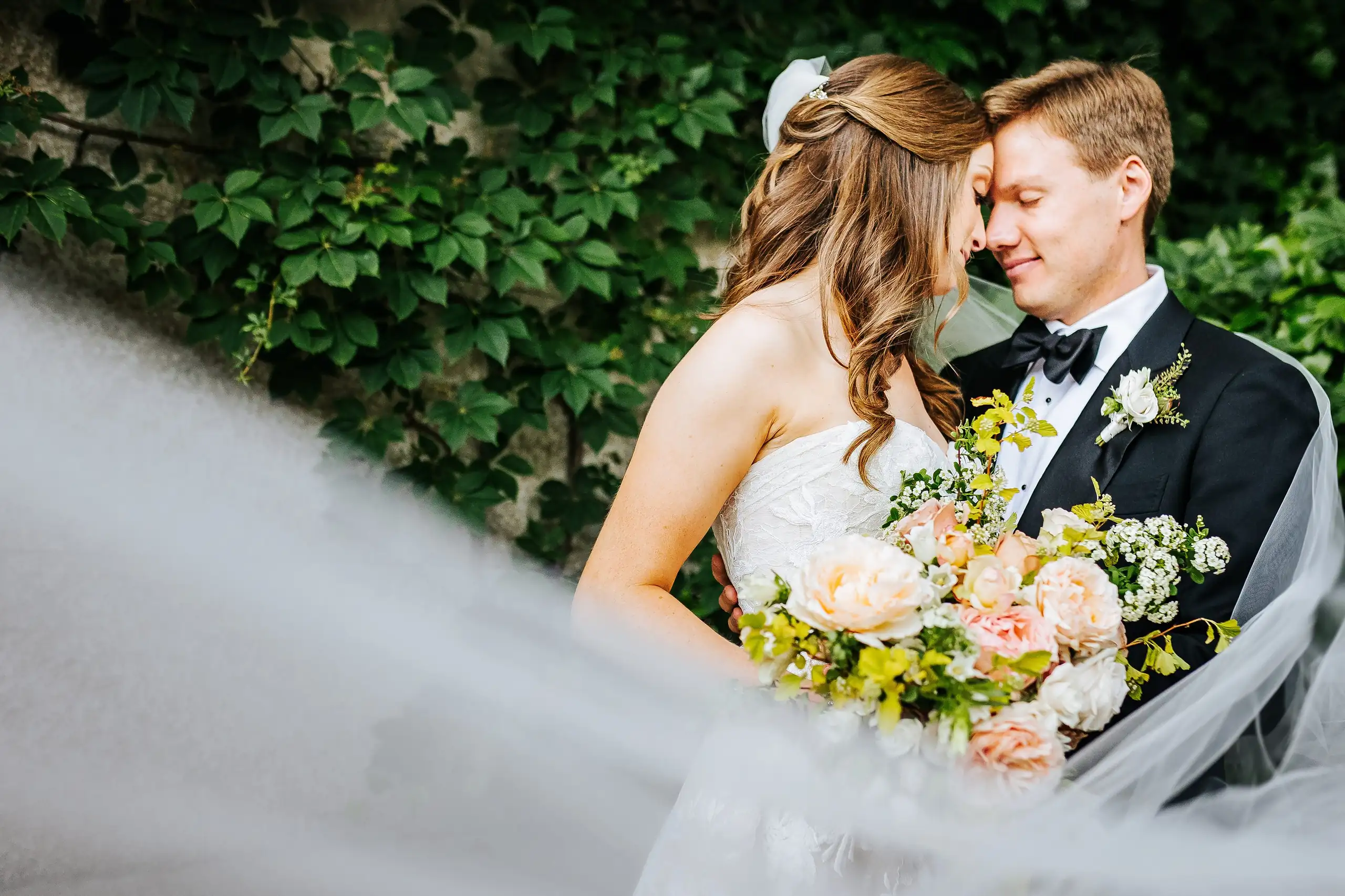 Wedding Formals: the bride's veil lifting as the couple stand in the greenery, at their wedding at Summerour Studio in Atlanta, GA