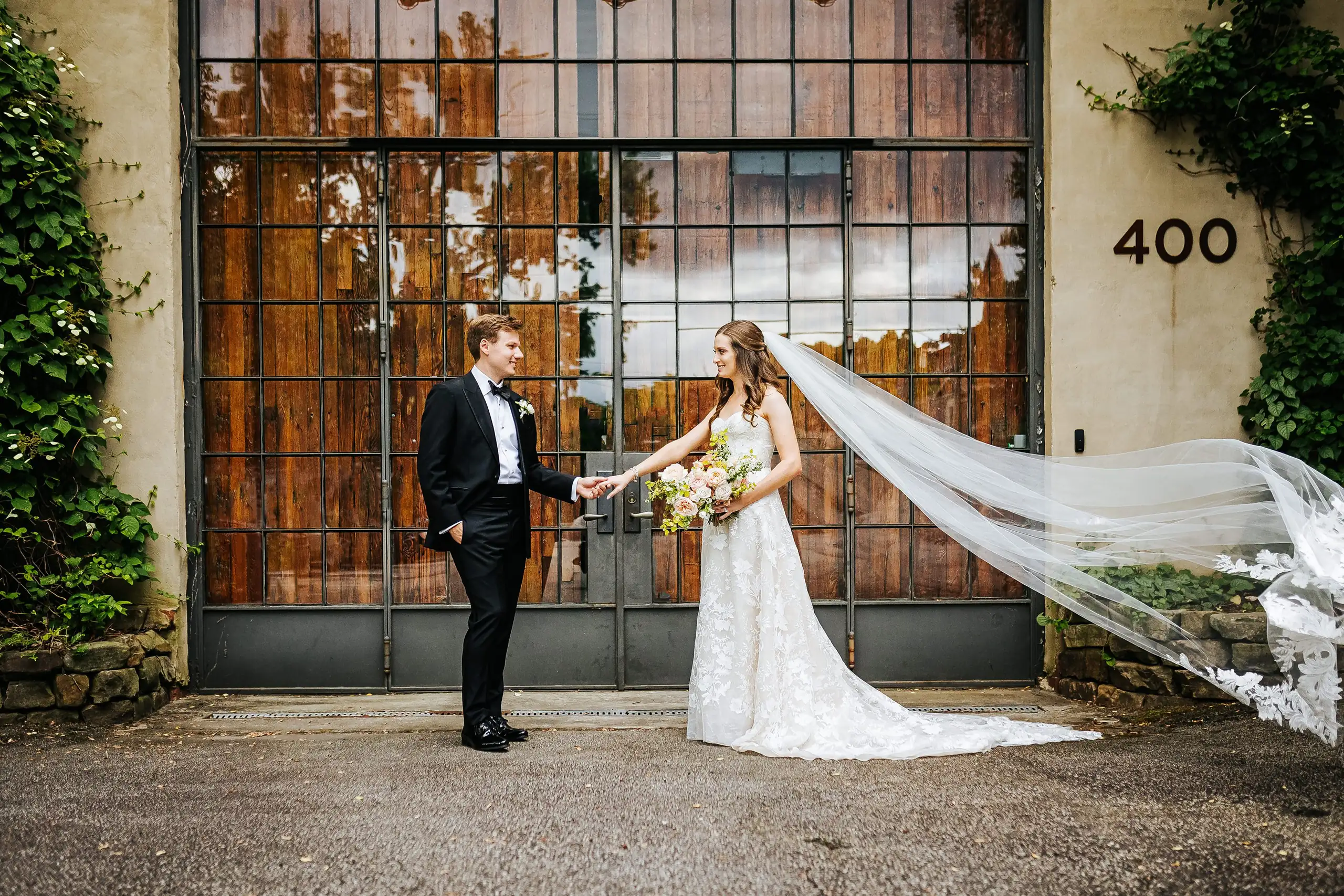 Wedding Formals: the couple by the warehouse doors with the veil flowing, at their wedding at Summerour Studio in Atlanta, GA