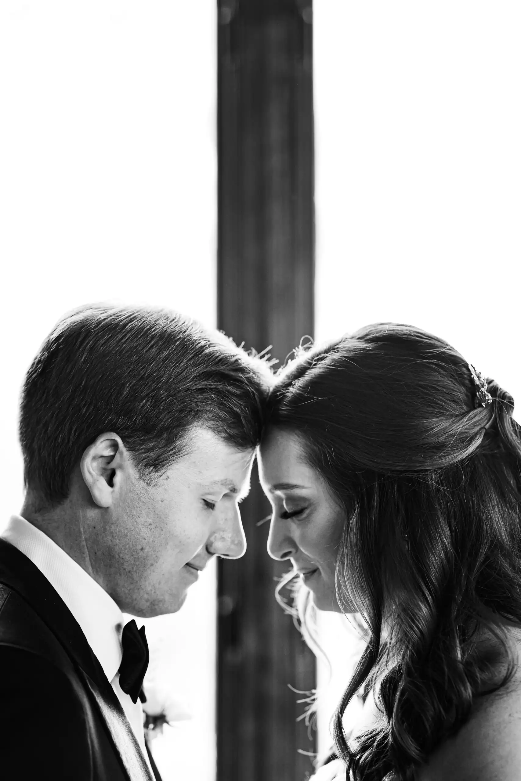 Wedding Formals: the couple forehead to forehead between the columns, in black and white, at their wedding at Summerour Studio in Atlanta, GA