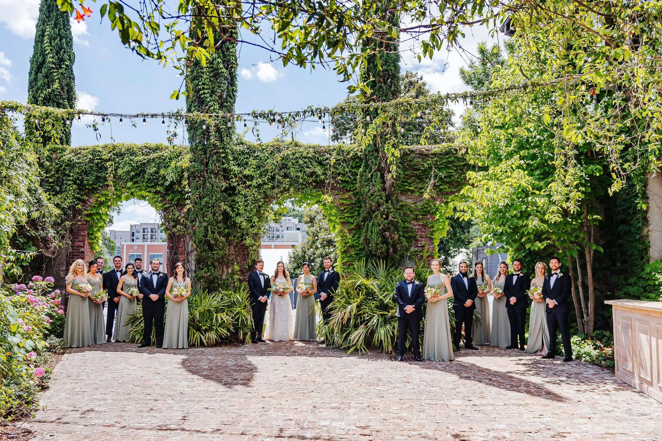 Wedding Party: the full wedding party across the ivy courtyard, at their wedding at Summerour Studio in Atlanta, GA