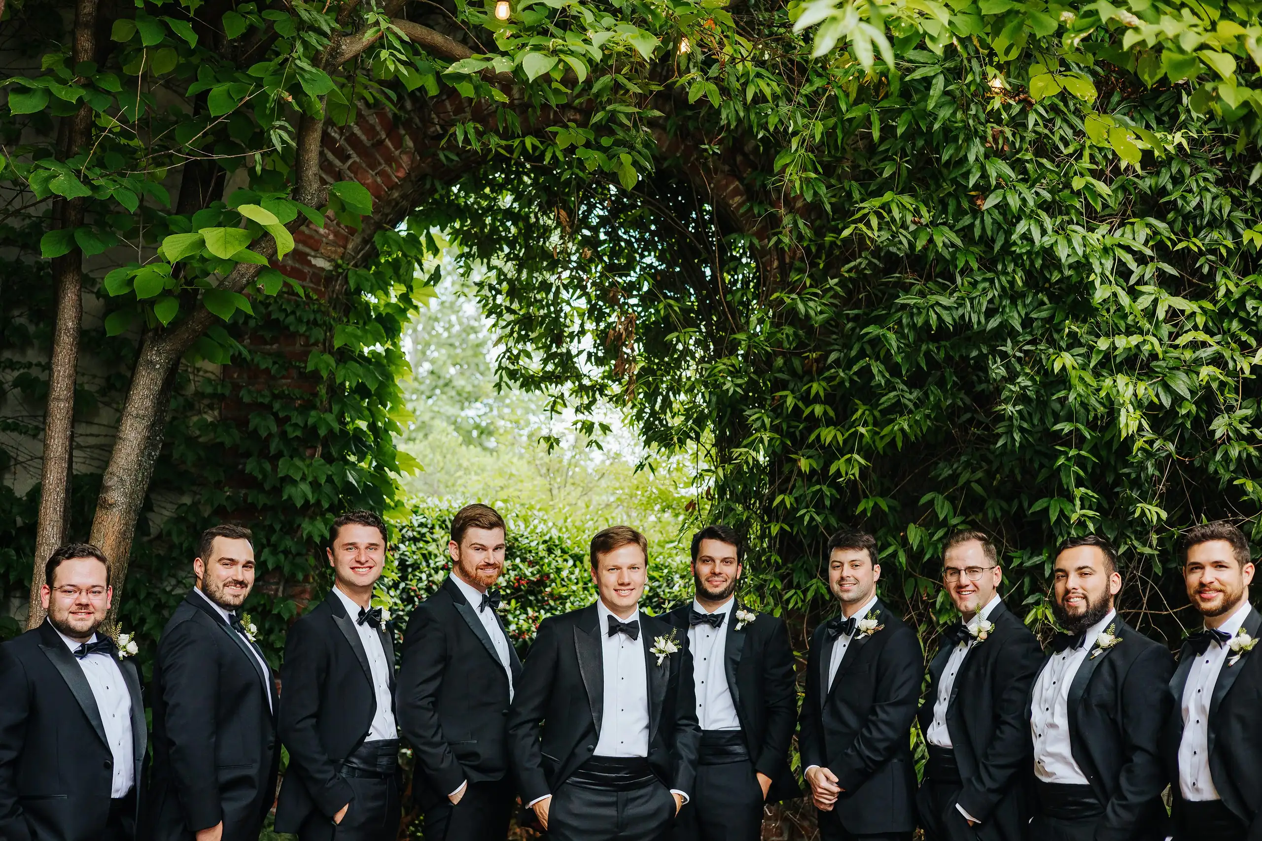Wedding Party: the groomsmen in tuxedos under the ivy, at their wedding at Summerour Studio in Atlanta, GA