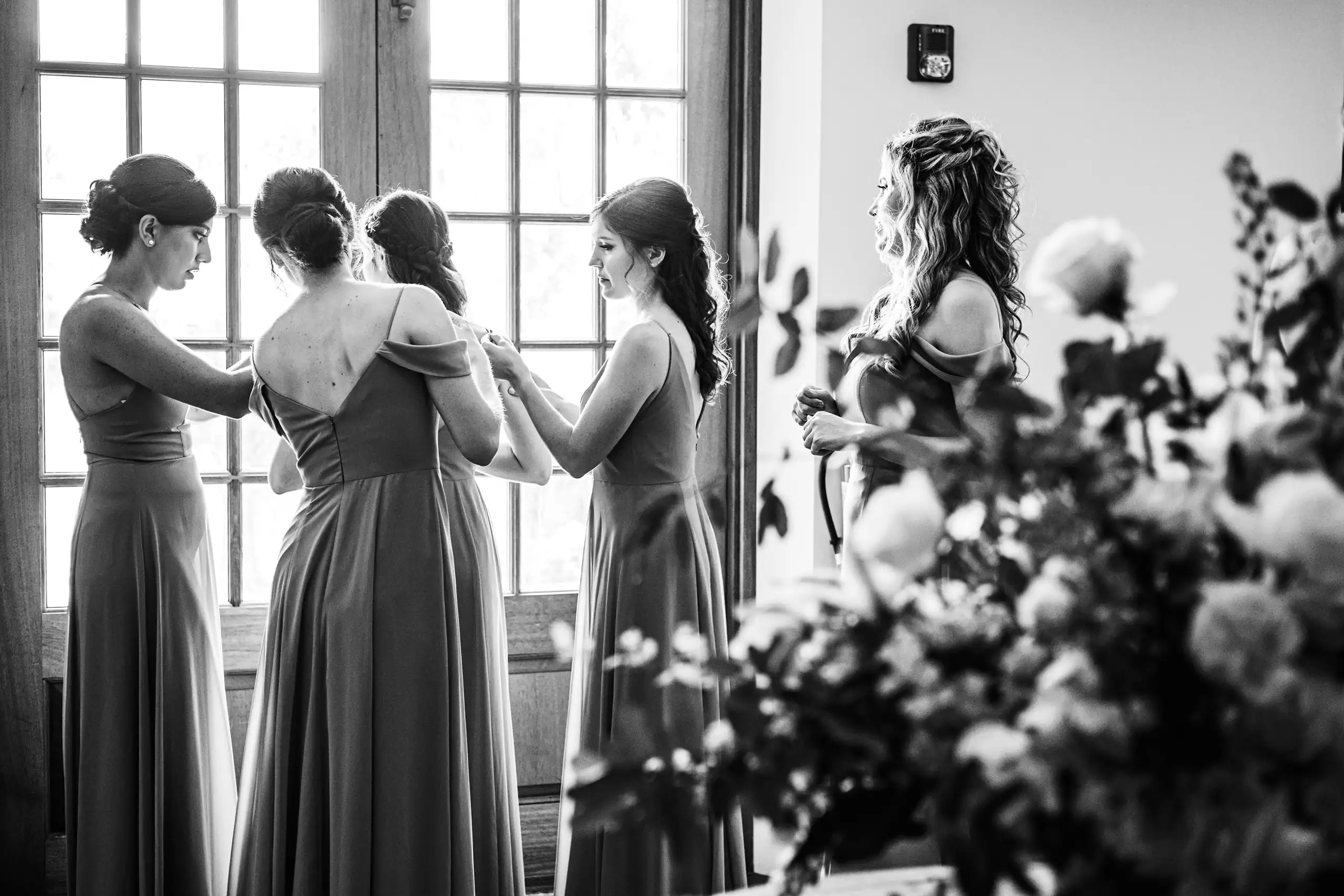 Getting Ready: bridesmaids helping the bride dress, in black and white, before their wedding at Summerour Studio in Atlanta, GA
