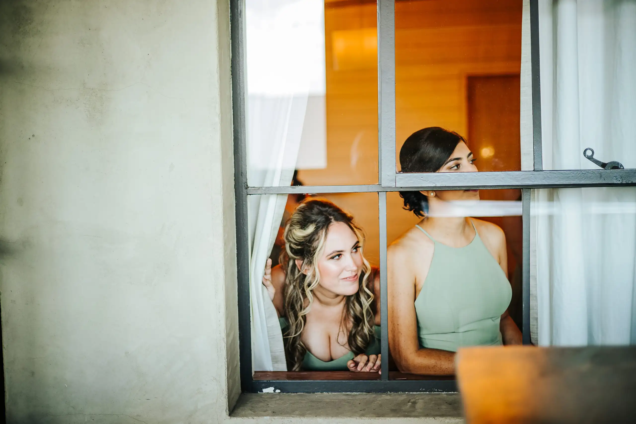 Getting Ready: the bride and a bridesmaid at the window, before their wedding at Summerour Studio in Atlanta, GA