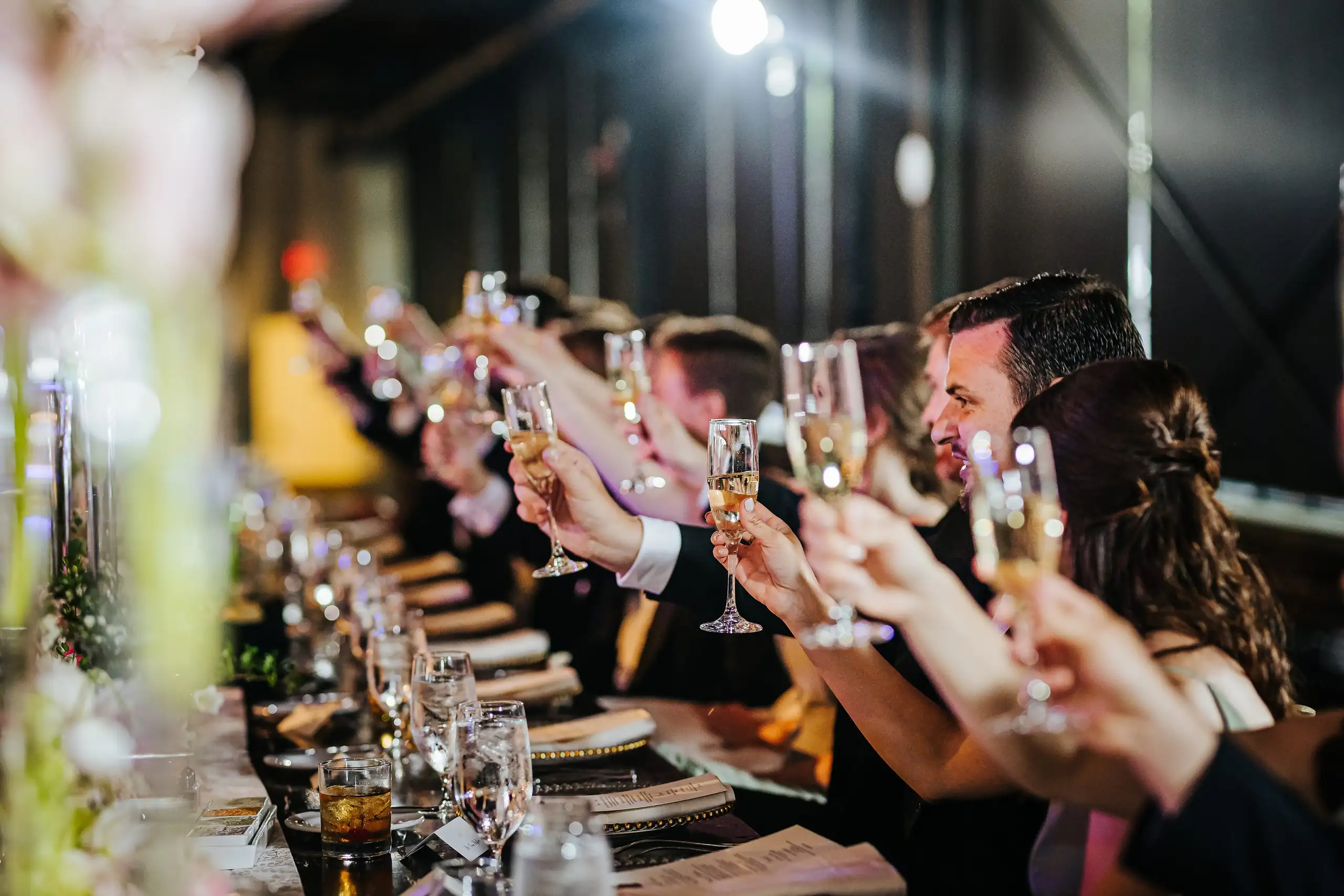 Wedding Reception: guests raising their glasses down the table, at their wedding at Summerour Studio in Atlanta, GA