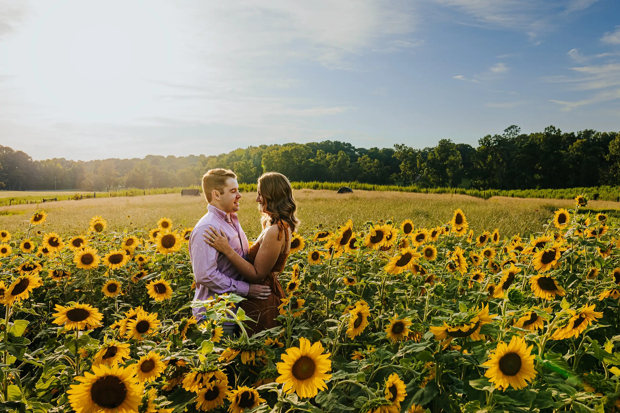 Engagement Portraits: the couple facing each other deep in the sunflowers, during their engagement session at Prospect Farms in Lawrenceville, GA