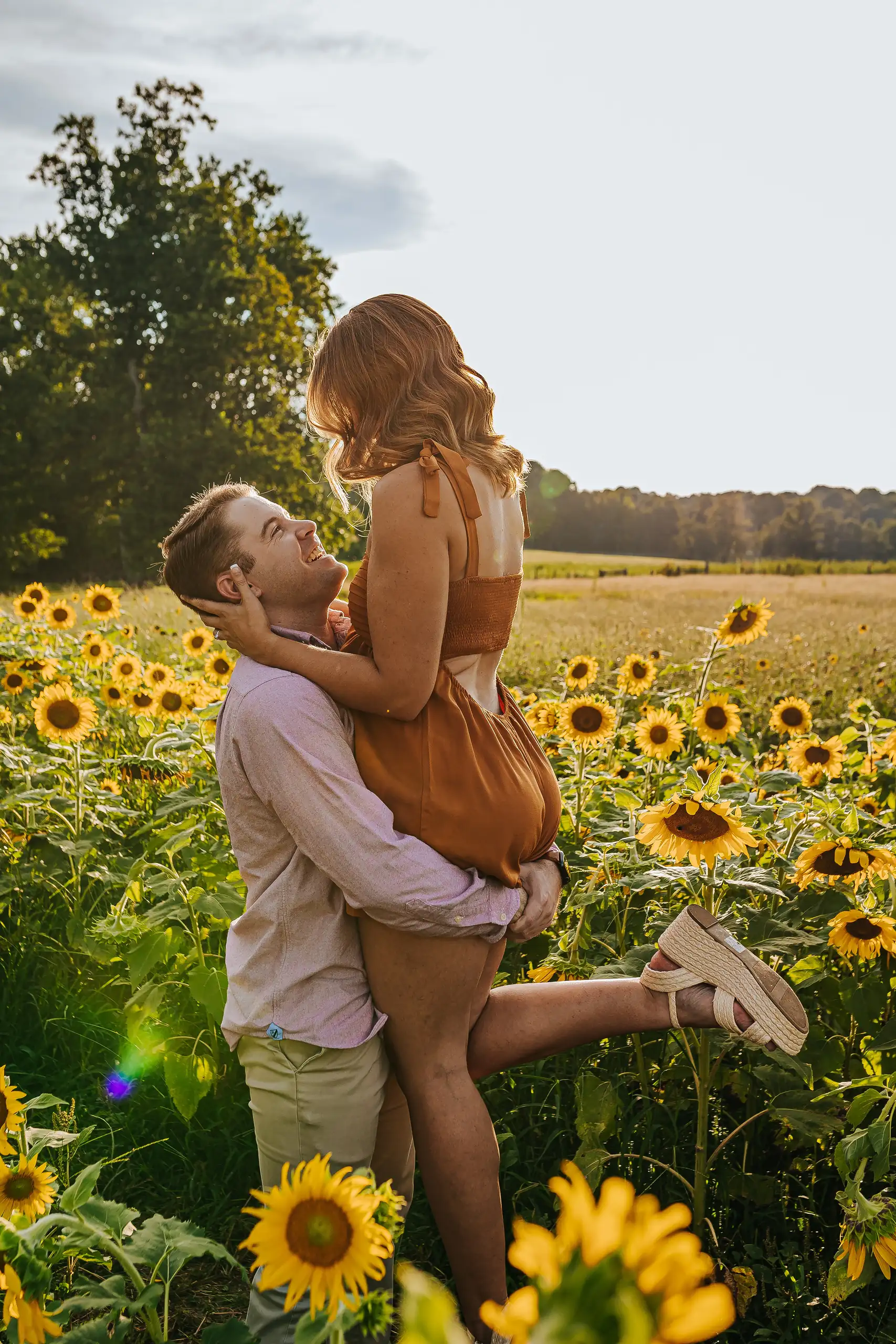 Engagement Portraits: her lifted up above the flower heads, during their engagement session at Prospect Farms in Lawrenceville, GA