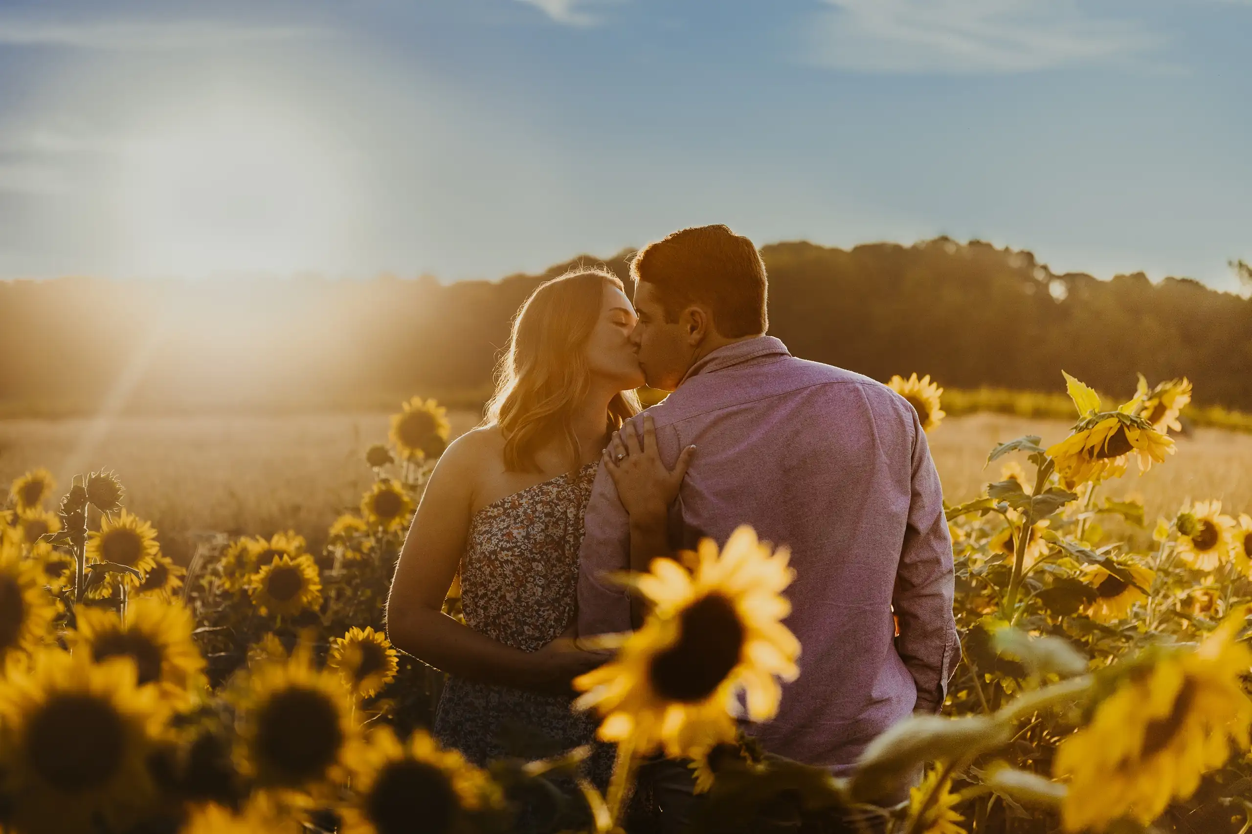 Engagement Portraits: a kiss with the sun going down behind the field, during their engagement session at Prospect Farms in Lawrenceville, GA