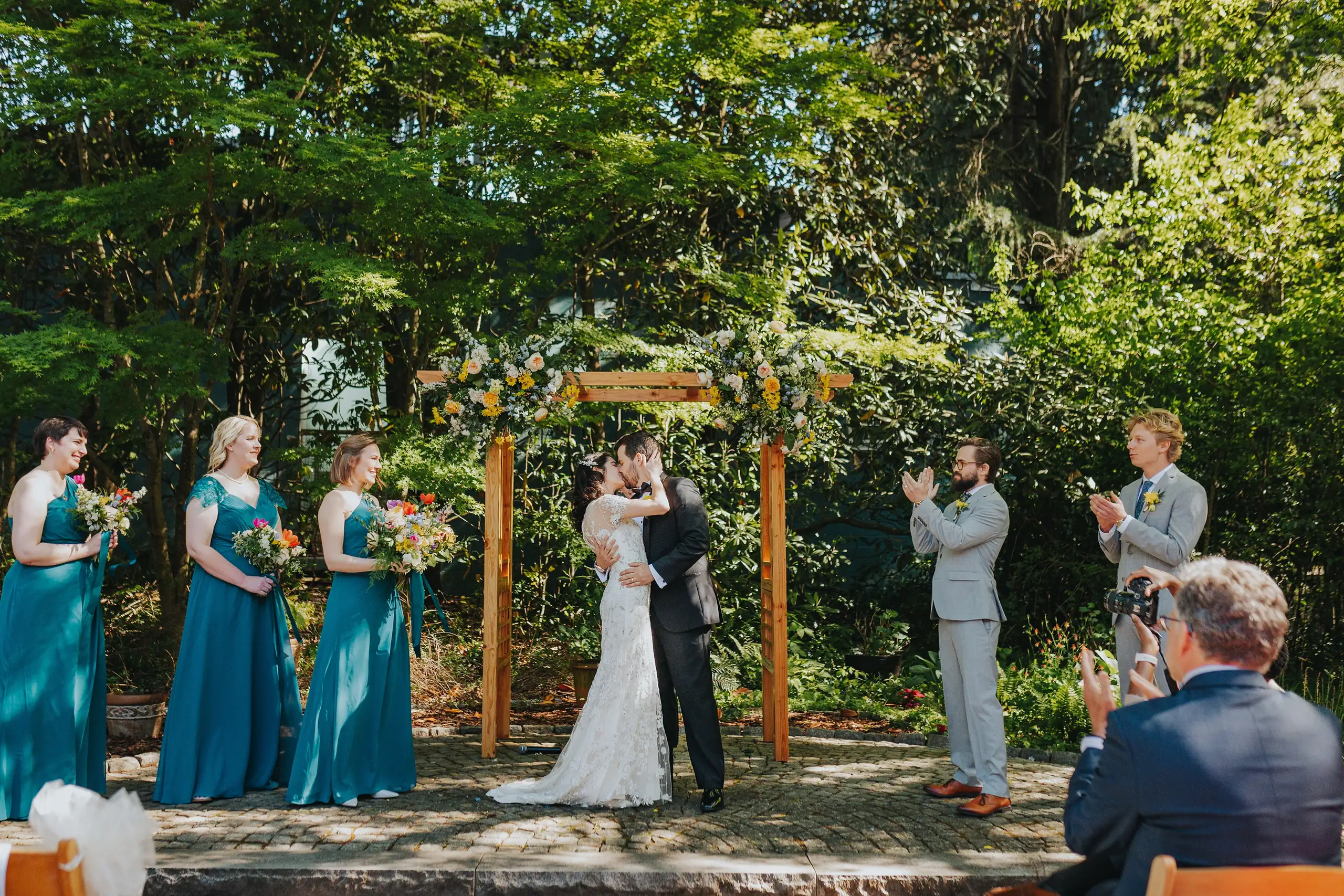 Wedding Ceremony: the ceremony among the trees, guests all around, at their wedding at the Trolley Barn in Atlanta, GA