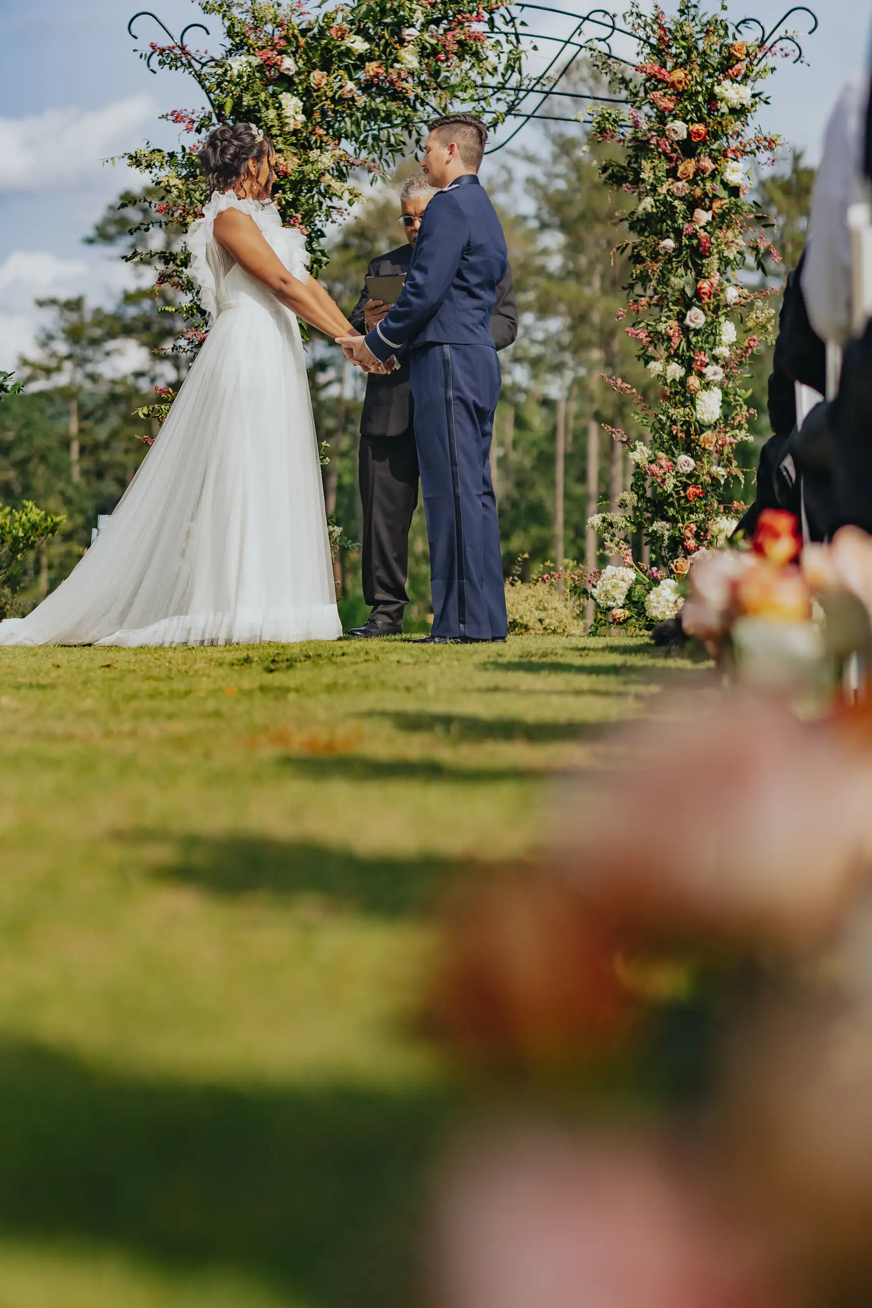 Wedding Ceremony: the couple before the officiant at the rose arch, at their wedding at Callaway Gardens in Pine Mountain, GA