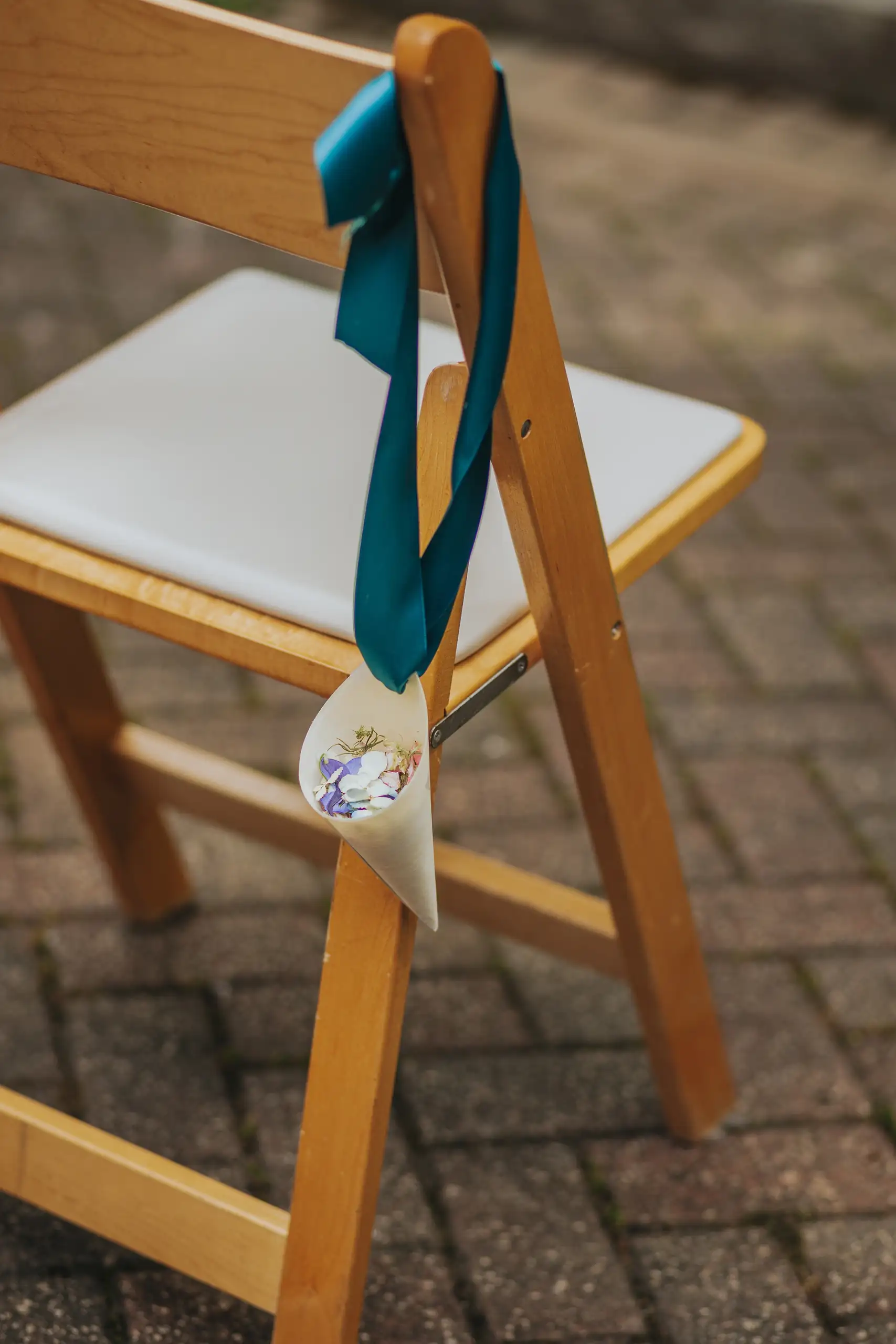 Wedding Details: a wooden chair tied with a teal ribbon and a flower, at a wedding at the Trolley Barn in Atlanta, GA