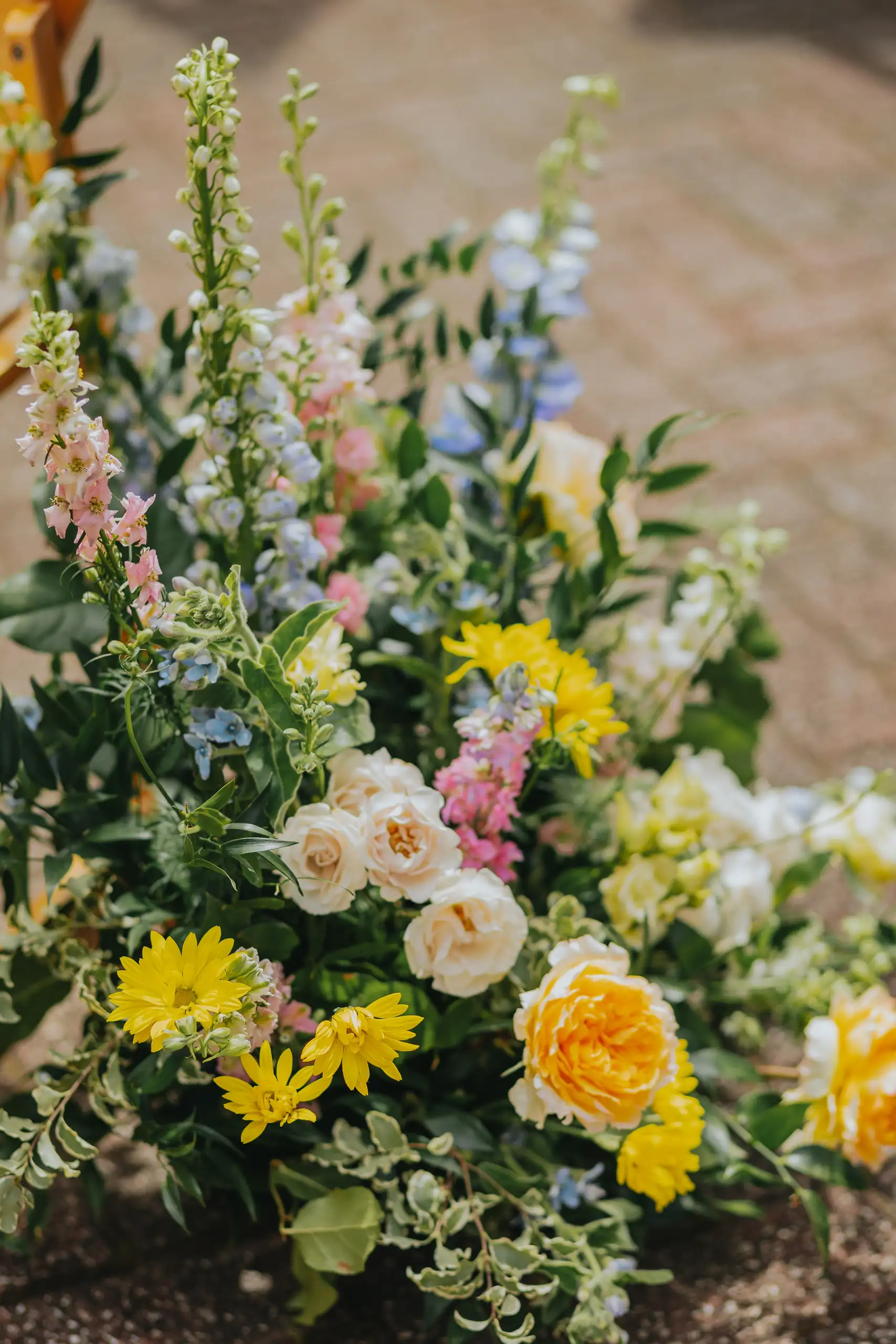 Wedding Florals: a yellow and peach arrangement set on the brick, at a wedding at the Trolley Barn in Atlanta, GA