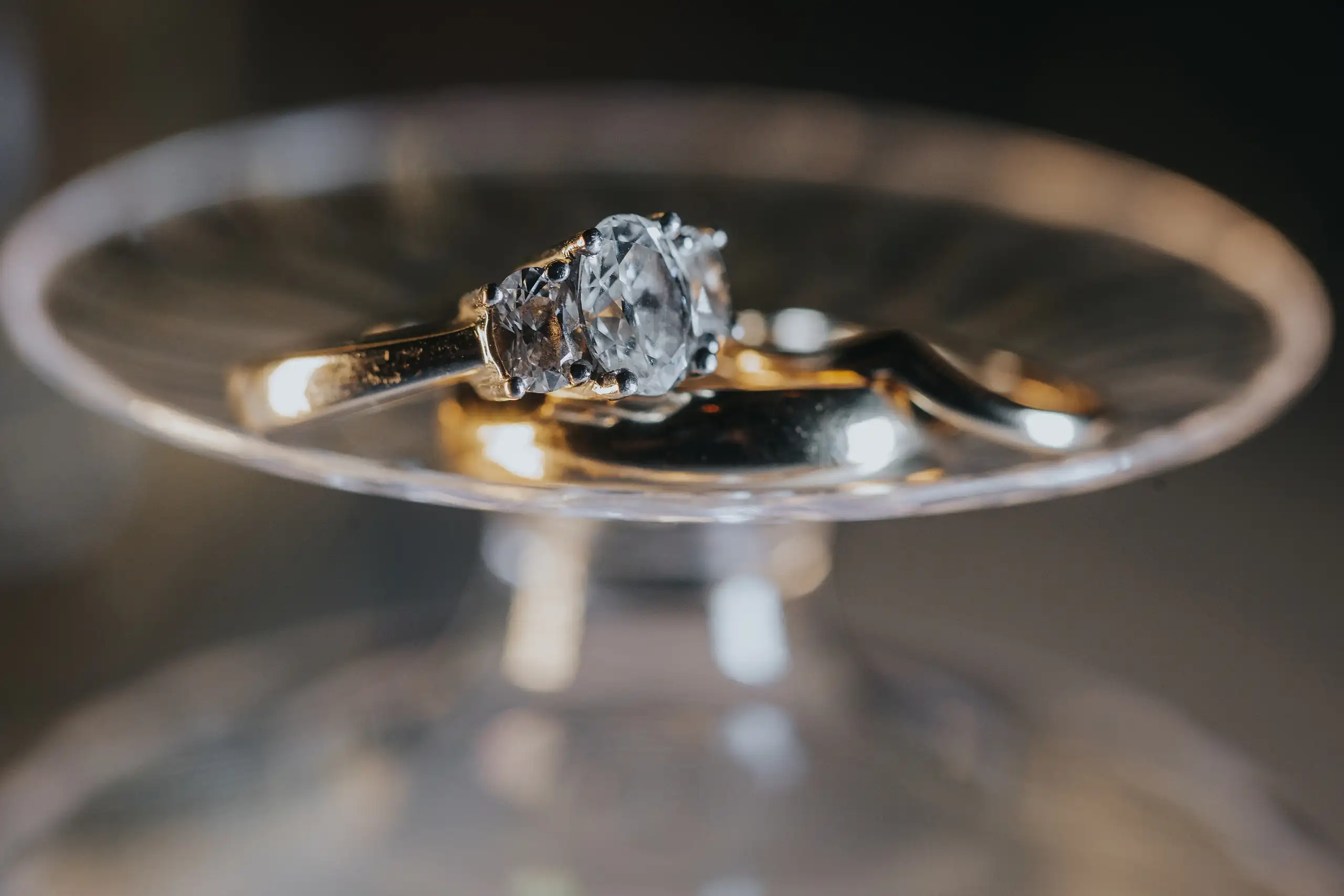 Wedding Details: the engagement ring balanced on a glass rim, at a wedding at the Trolley Barn in Atlanta, GA