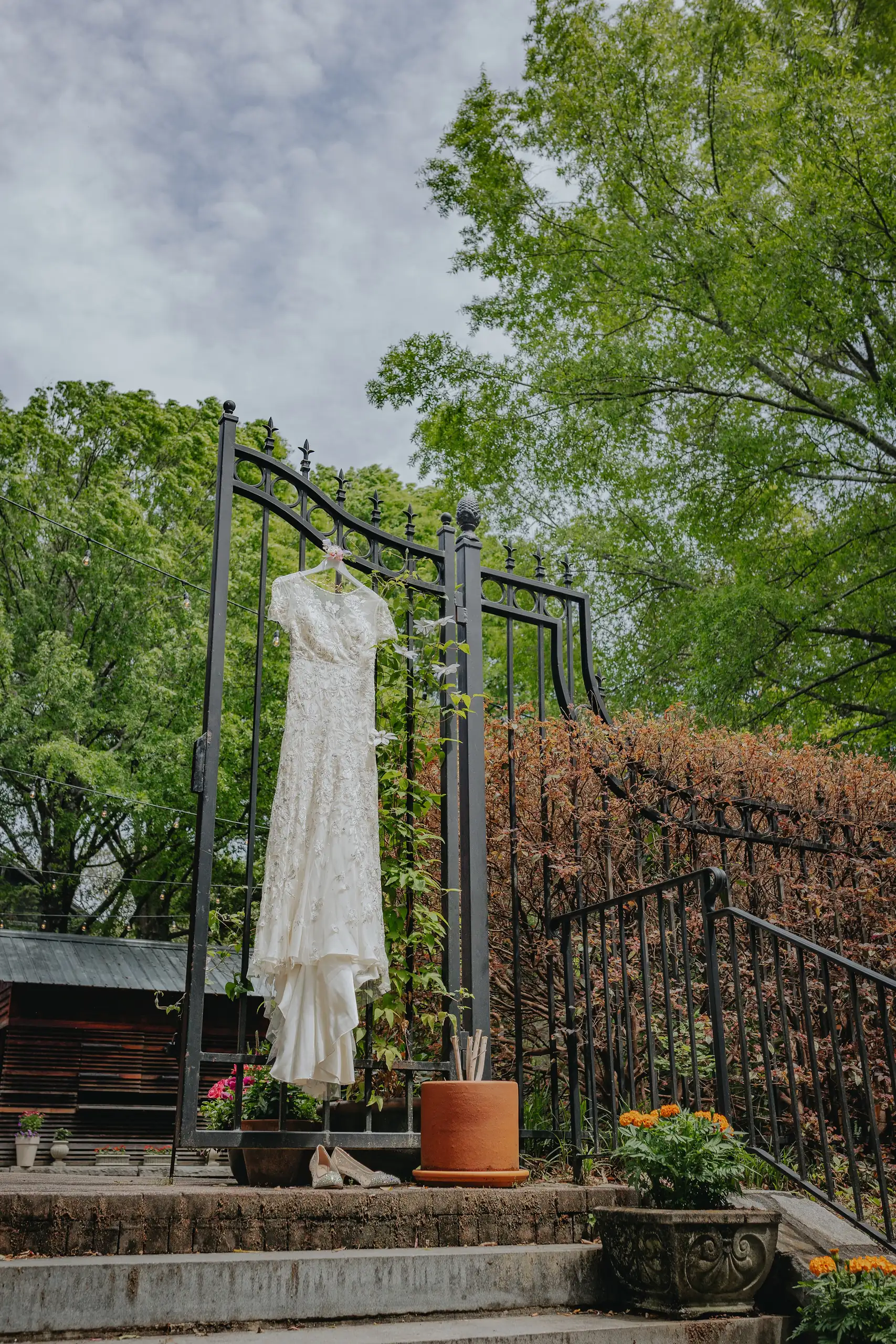 Wedding Details: the gown hanging on the stair rail among greenery, at a wedding at the Trolley Barn in Atlanta, GA