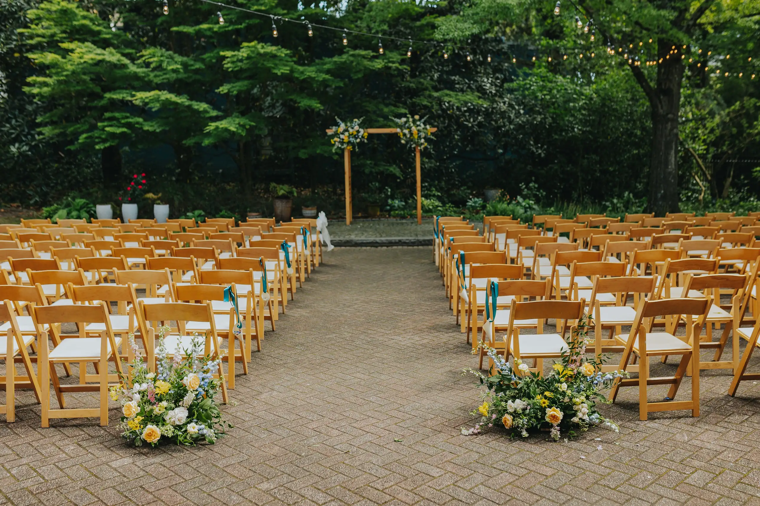 Wedding Ceremony: the ceremony set under a timber arch and string lights, at a wedding at the Trolley Barn in Atlanta, GA