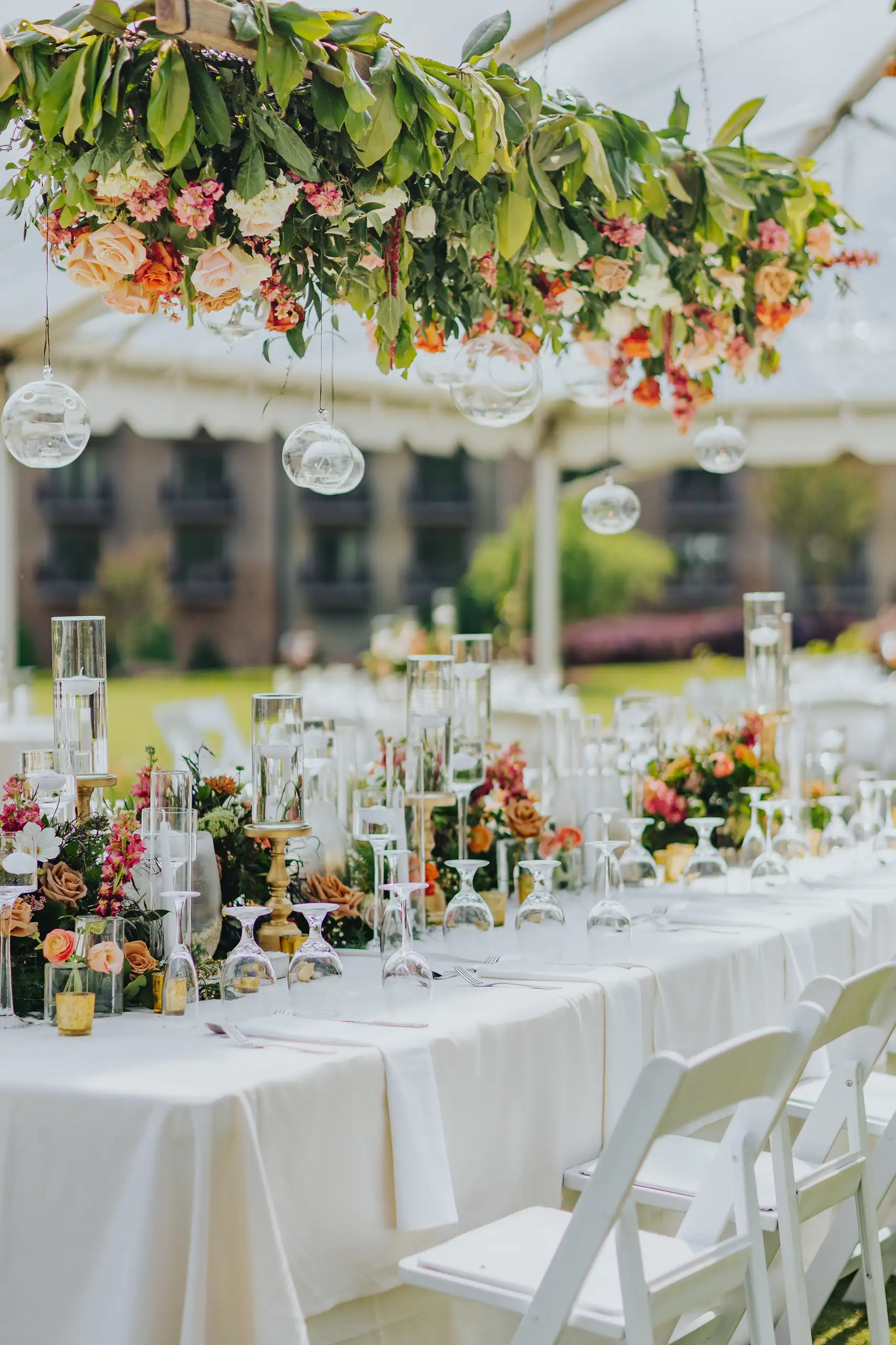Reception Details: the long table under the hanging florals in the tent, at a wedding at Callaway Gardens in Pine Mountain, GA