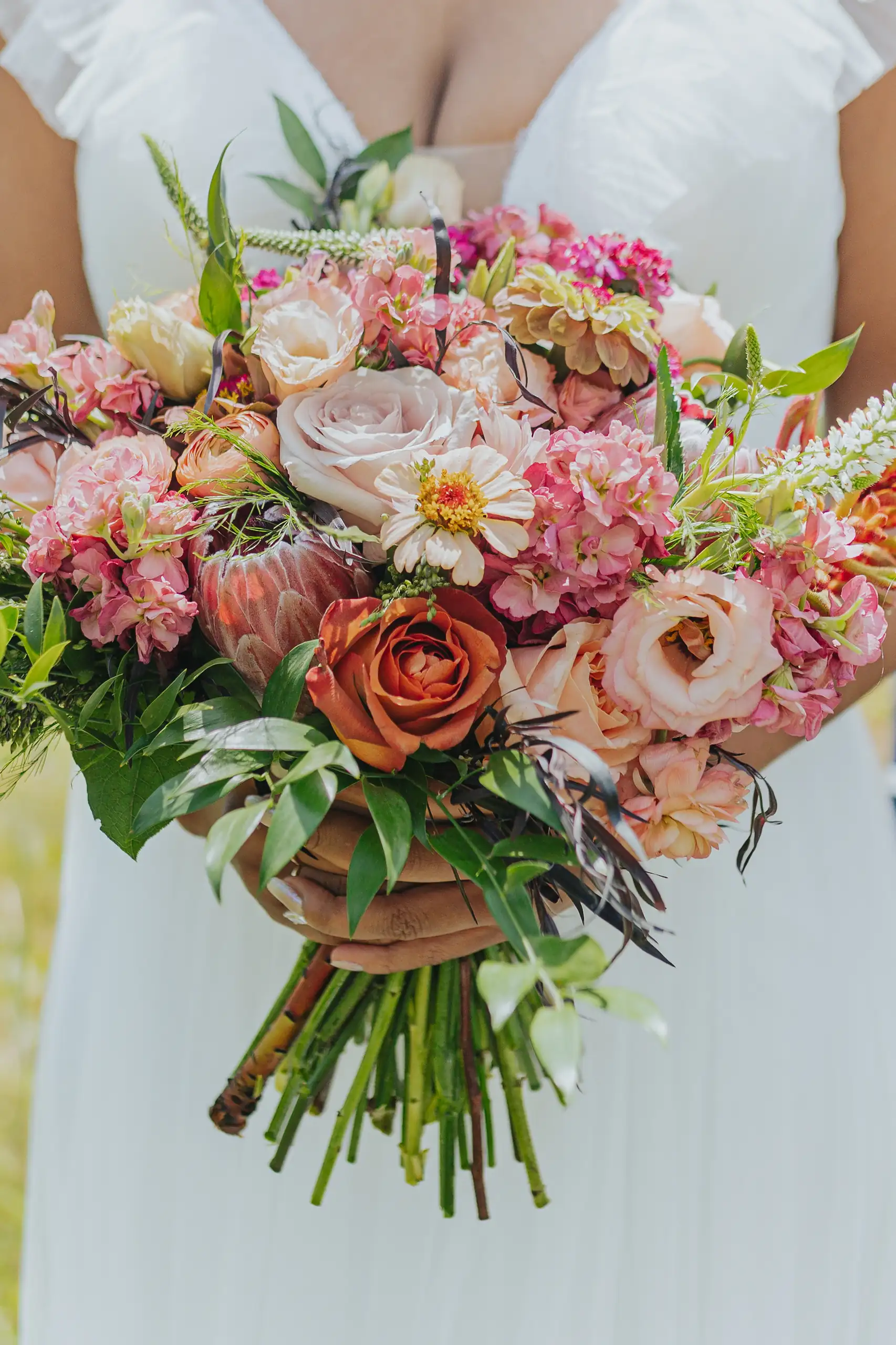 Wedding Florals: the bride holding her blush and coral bouquet, at their wedding at Callaway Gardens in Pine Mountain, GA