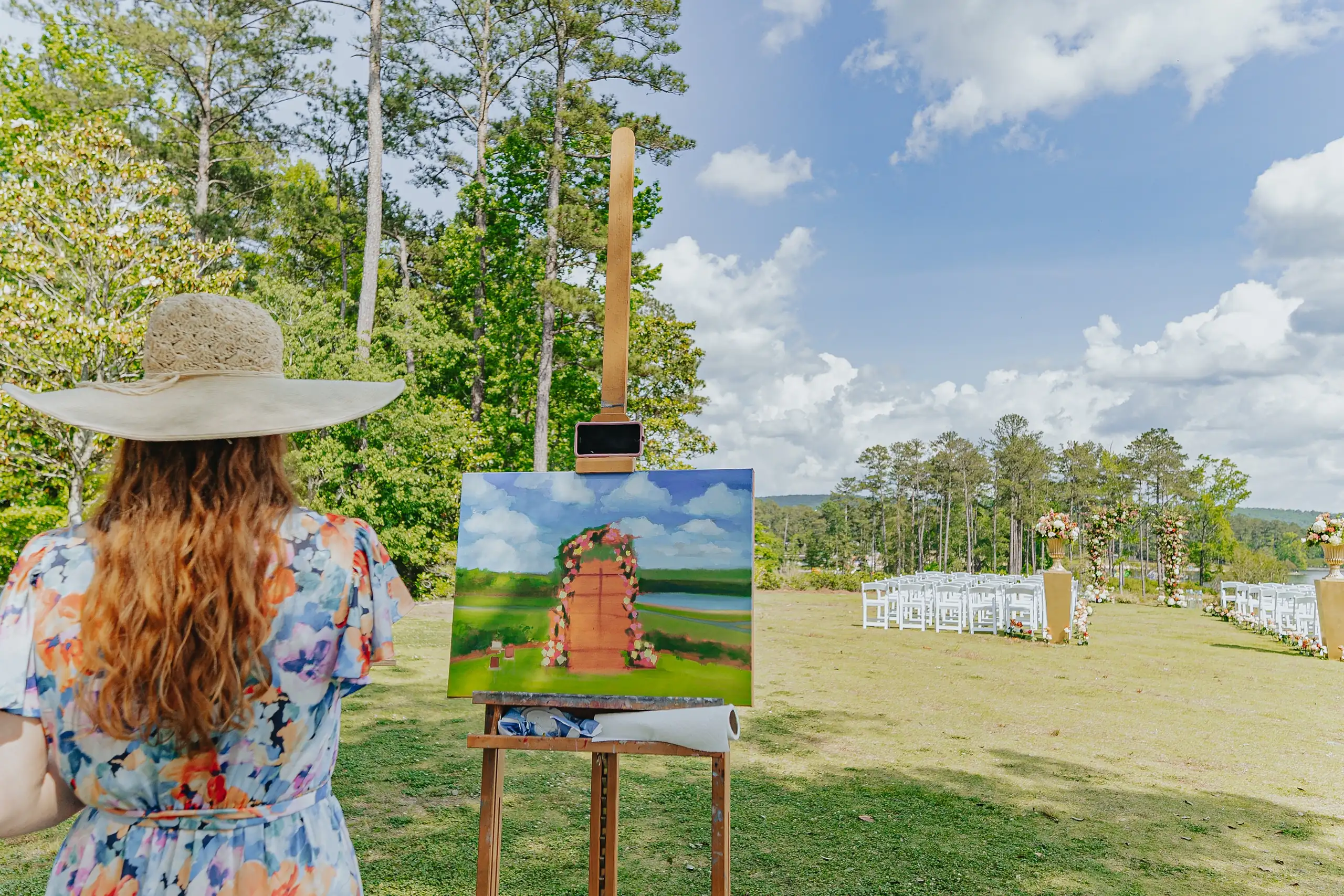 Wedding Ceremony: the live painter at her easel beside the aisle, at their wedding at Callaway Gardens in Pine Mountain, GA