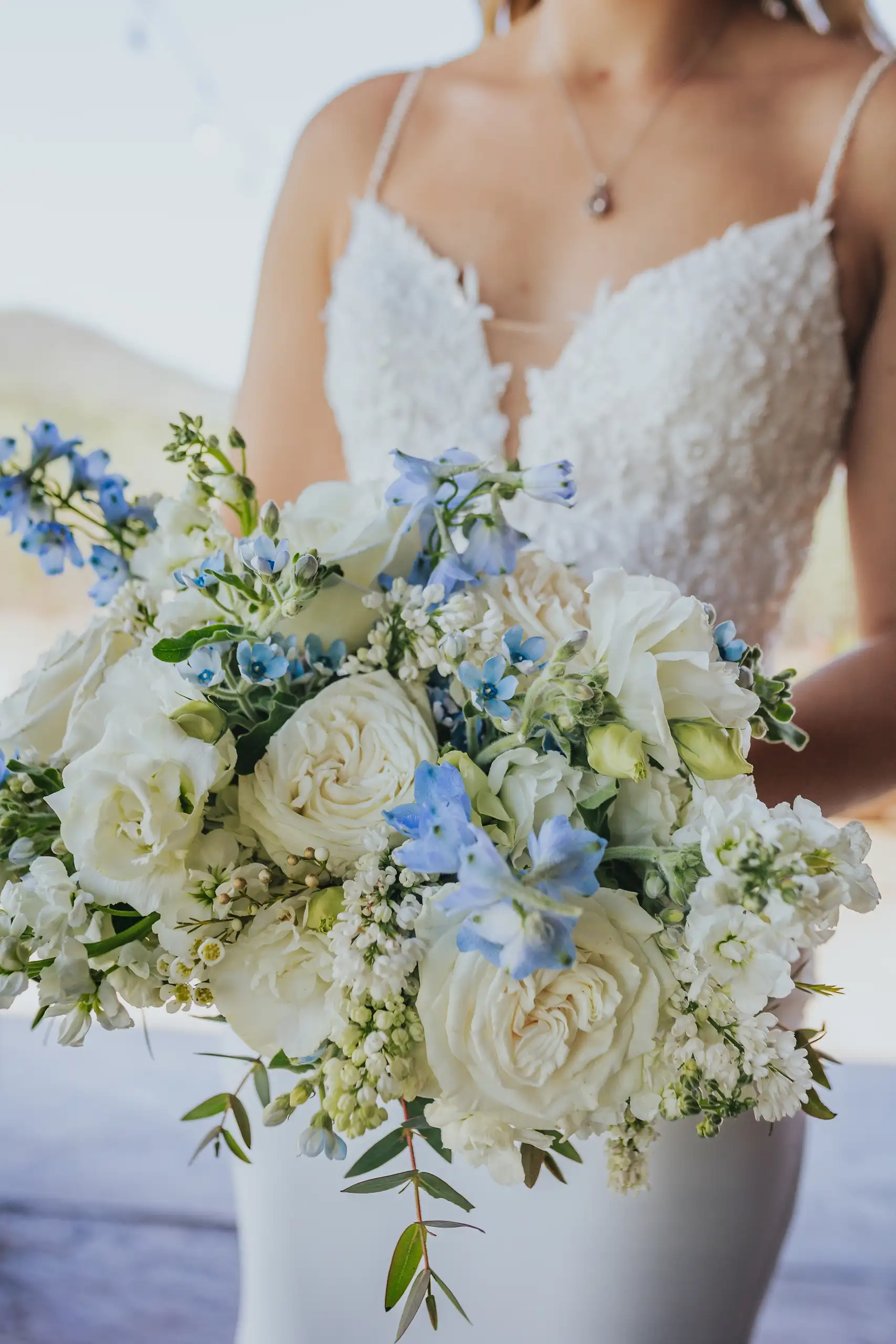 Wedding Florals: the bride holding her white and blue bouquet, at their wedding at The Venue at Sharp Mountain in Jasper, GA