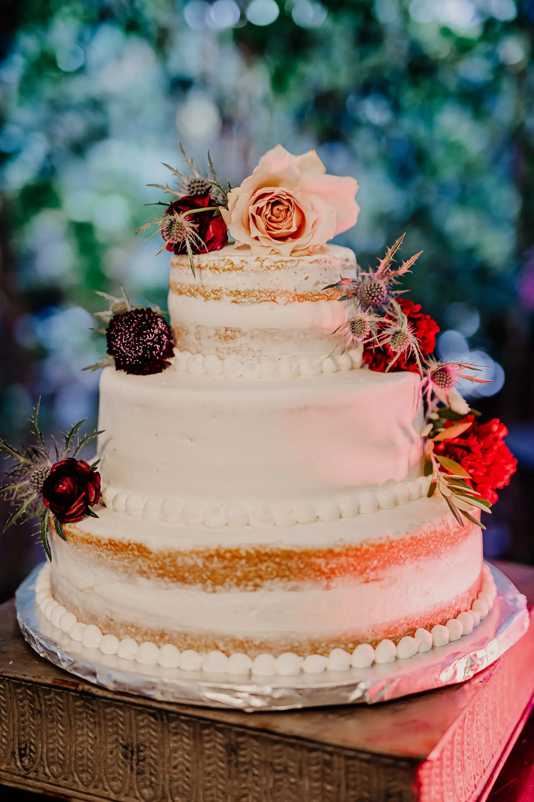 Wedding Cake Details: the part-naked cake dressed with dark blooms, at a wedding at Wahoo! Grill in Decatur, GA