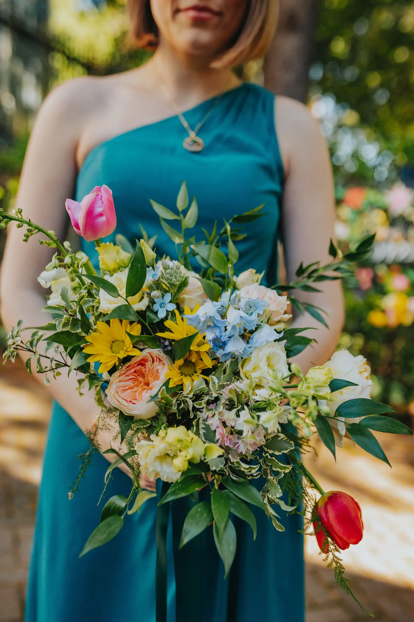Wedding Party: a bridesmaid in teal with her bright bouquet, at their wedding at the Trolley Barn in Atlanta, GA