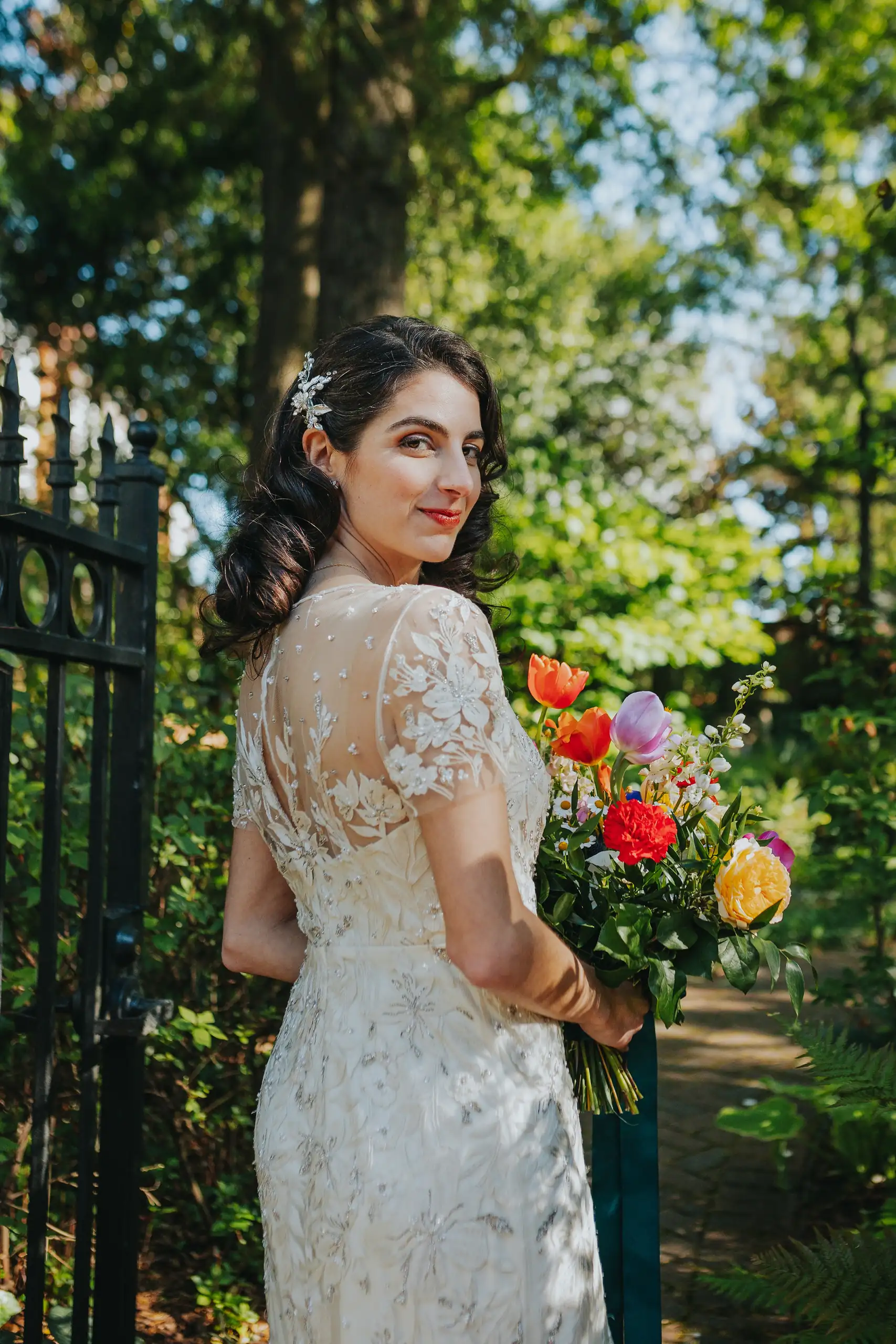 Bridal Portraits: the bride with her bouquet by the gate, at their wedding at the Trolley Barn in Atlanta, GA