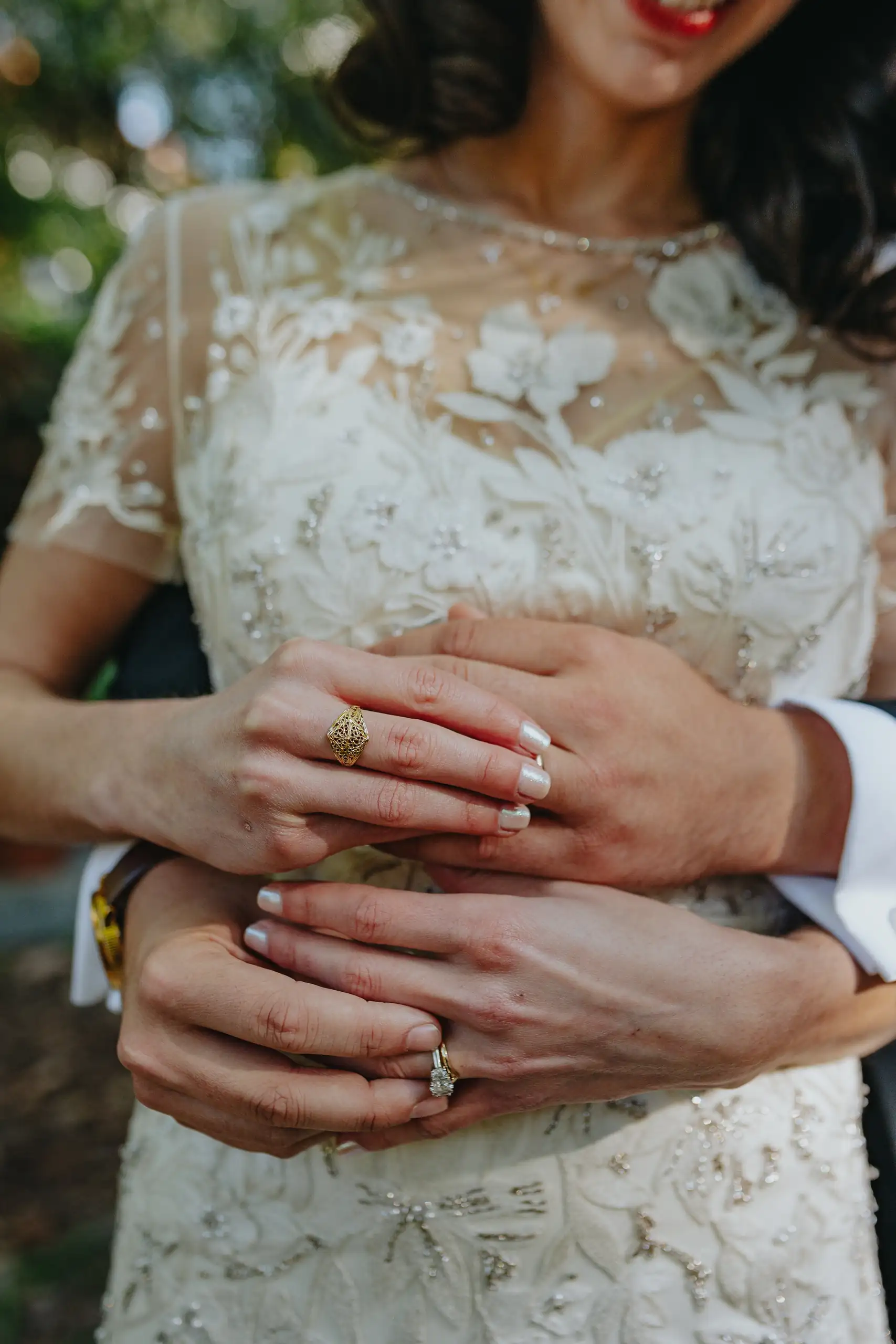 Wedding Details: the couple's hands together at her lace bodice, at a wedding at the Trolley Barn in Atlanta, GA