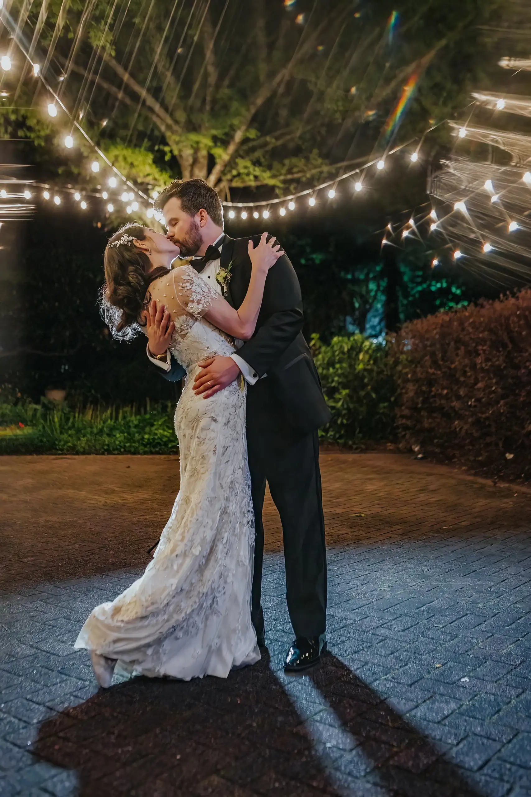 Wedding Formals: the couple kissing under the string lights, at their wedding at the Trolley Barn in Atlanta, GA