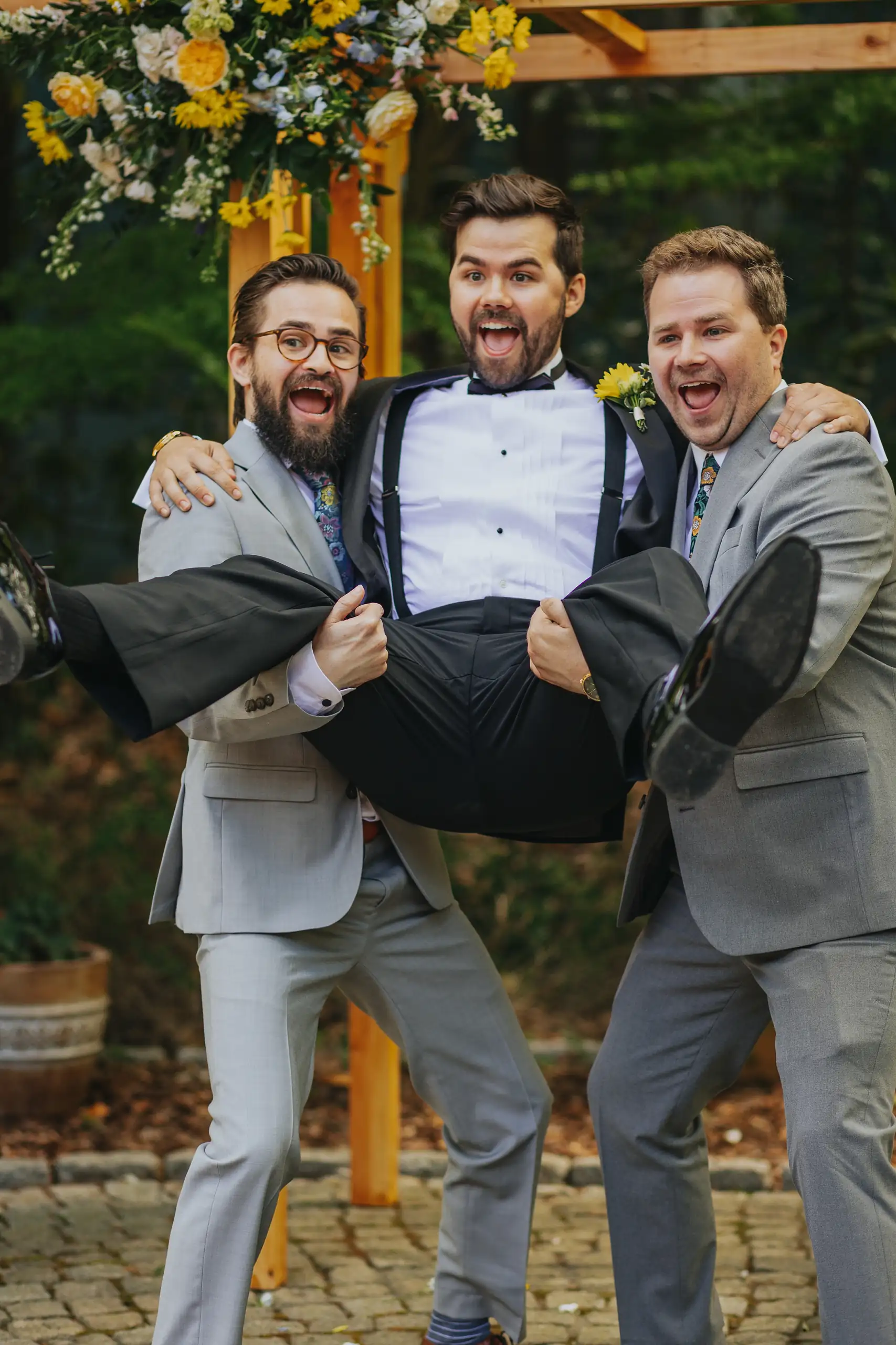 Wedding Party: the groomsmen lifting the groom off his feet, at their wedding at the Trolley Barn in Atlanta, GA