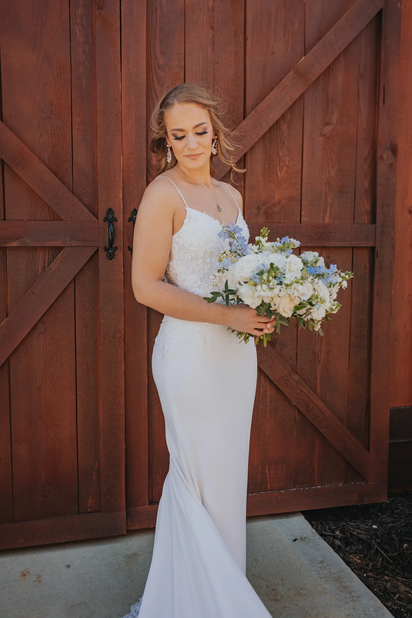 Bridal Portraits: the bride with her bouquet at the barn doors, at their wedding at The Venue at Sharp Mountain in Jasper, GA