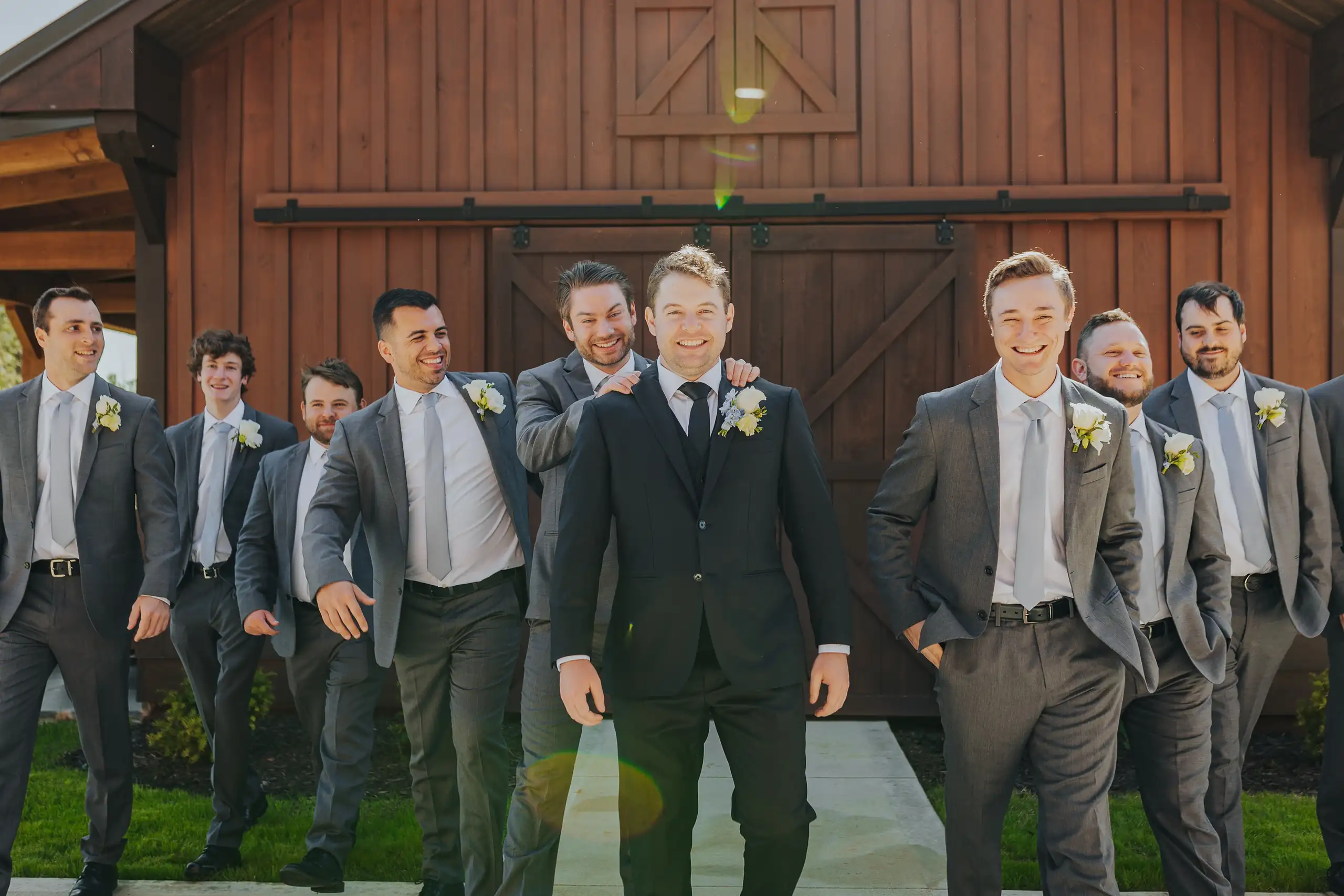 Wedding Party: the groomsmen laughing at the barn doors, at their wedding at The Venue at Sharp Mountain in Jasper, GA