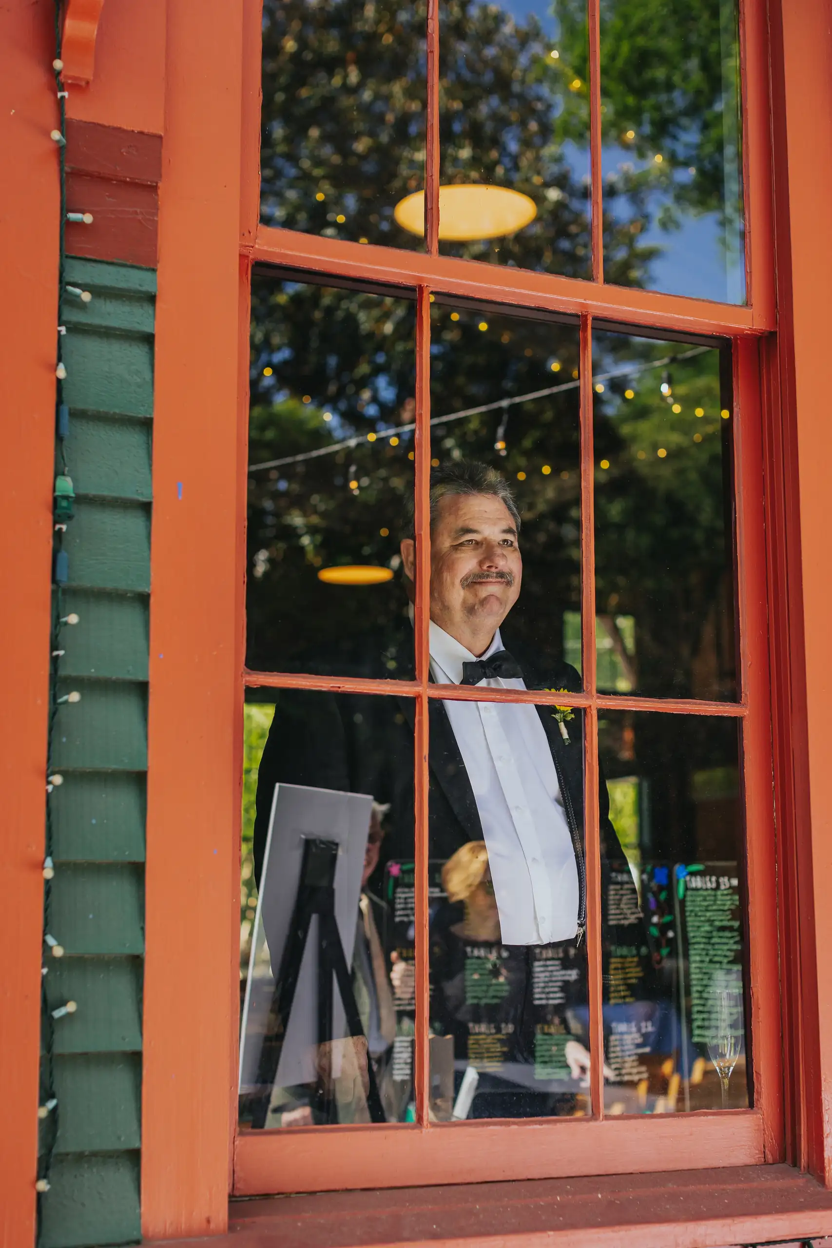 Getting Ready: the groom seen through an orange window frame, before their wedding at the Trolley Barn in Atlanta, GA